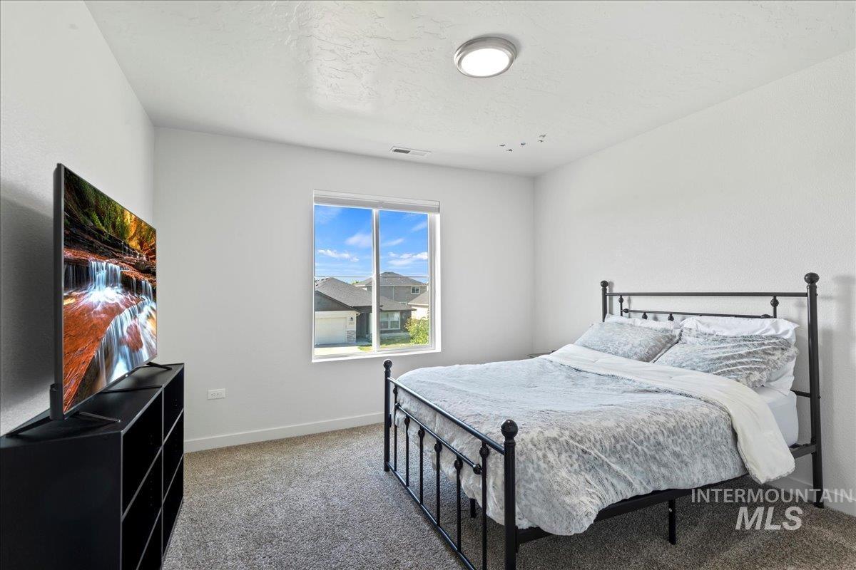 Carpeted bedroom with a textured ceiling and baseboards
