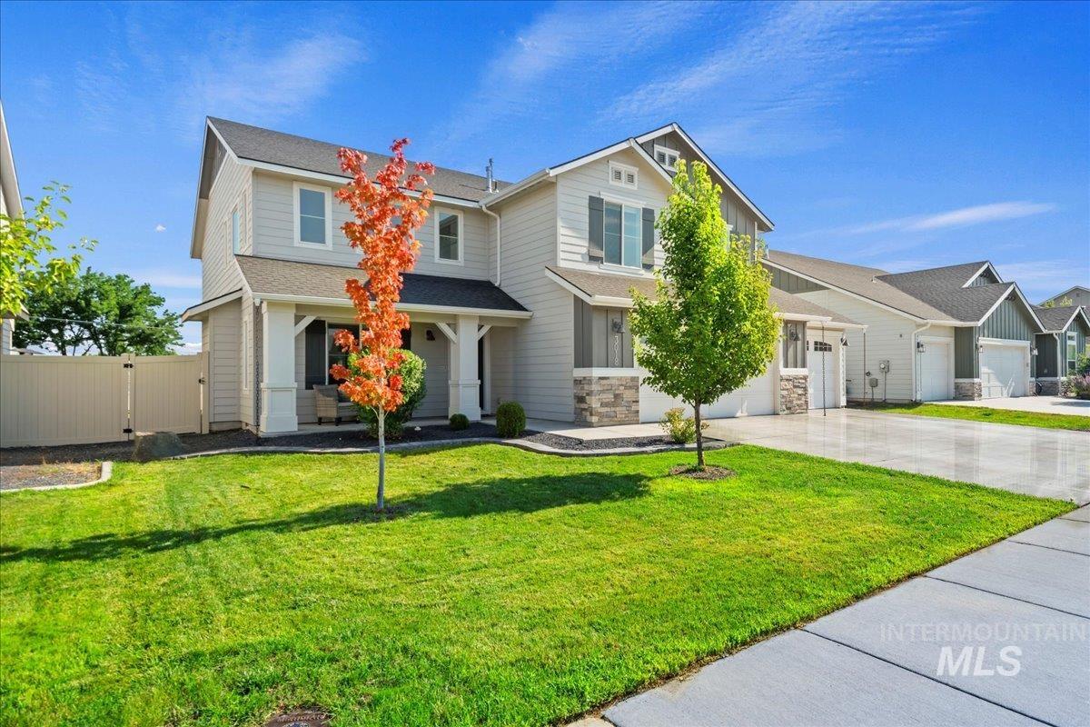 View of front of home with driveway, a gate, an attached garage, a shingled roof, and stone siding