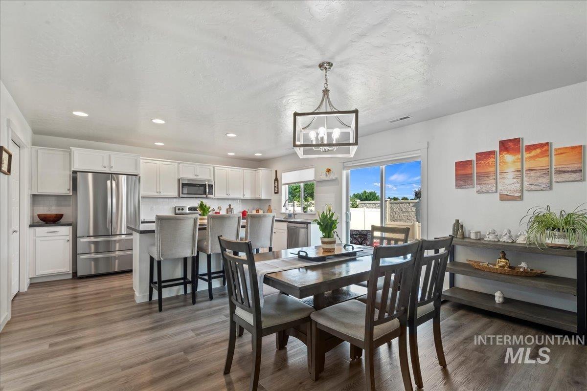 Dining space with a chandelier, recessed lighting, engineered vinyl plank-type flooring, and a textured ceiling