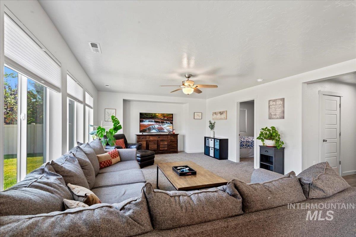 Carpeted living area featuring ceiling fan