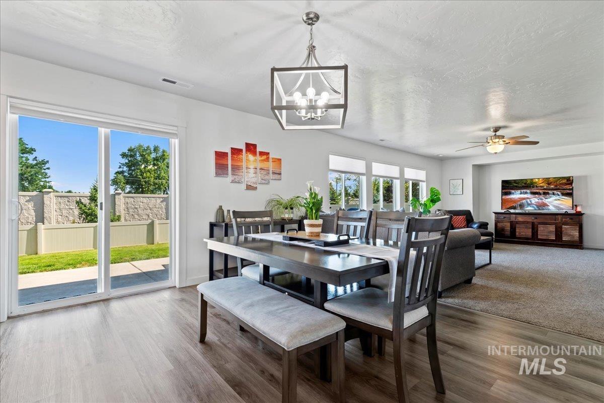 Dining room featuring a textured ceiling, a chandelier, engineered vinyl plank-type flooring, and a ceiling fan