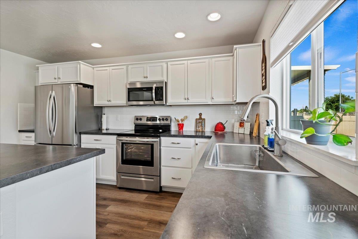 Kitchen featuring dark countertops, appliances with stainless steel finishes, white cabinetry, and recessed lighting