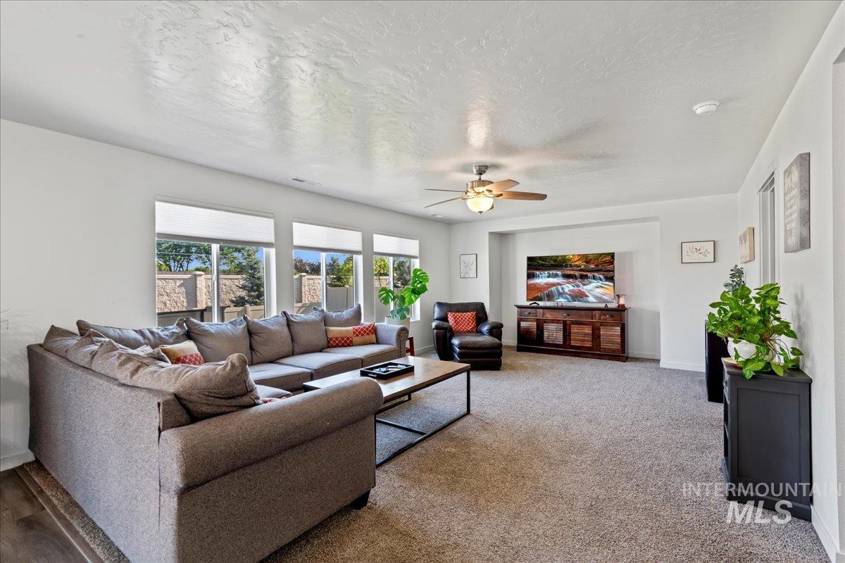 Carpeted living area featuring a textured ceiling and ceiling fan