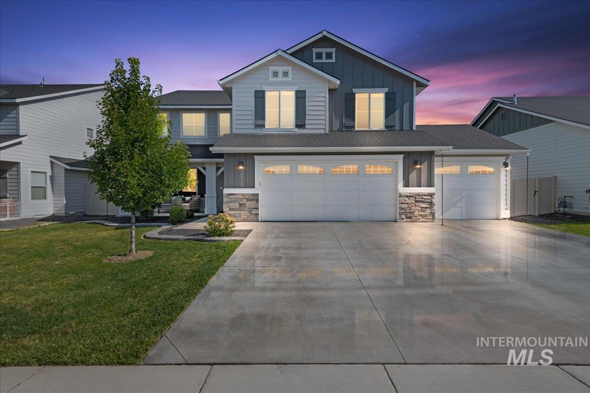 View of front of house with stone siding, board and batten siding, driveway, and a yard