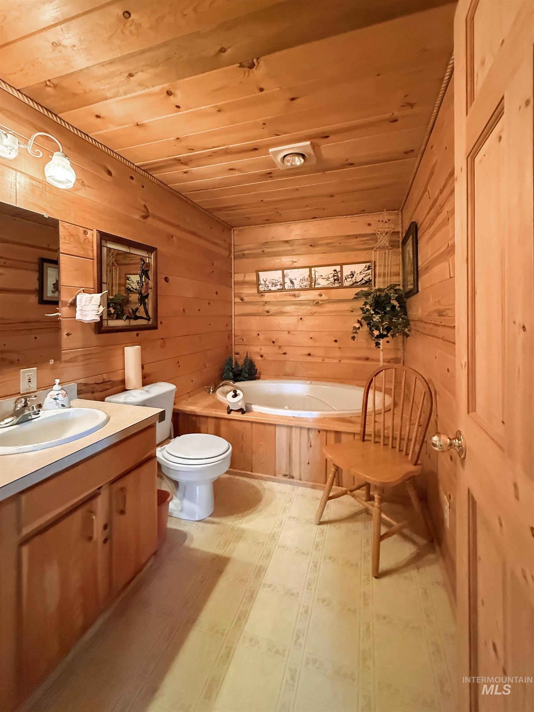 Bathroom with wood ceiling, a garden tub, wood walls, and vanity