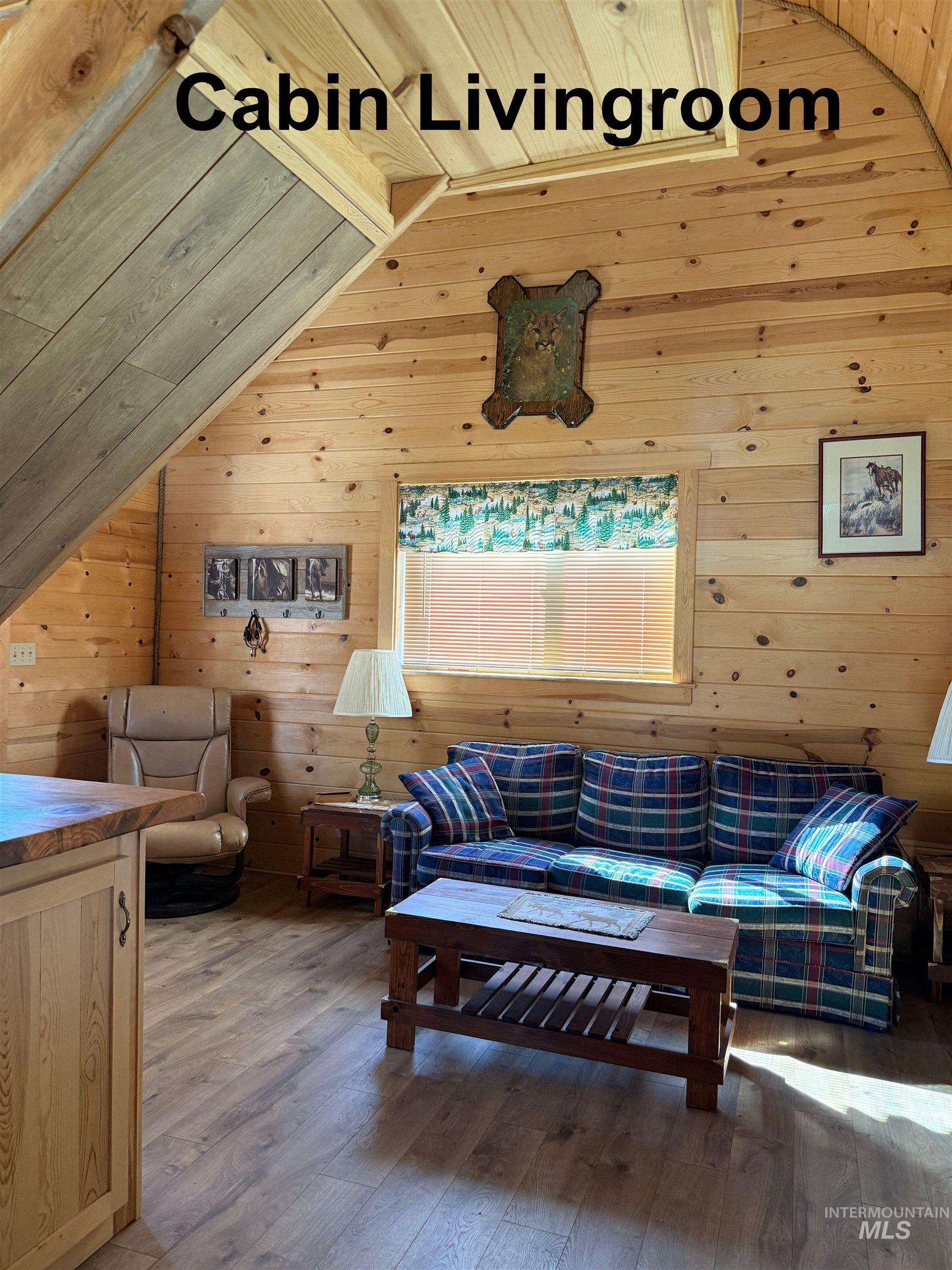 Living room featuring wood walls, lofted ceiling, hardwood / wood-style floors, and wooden ceiling