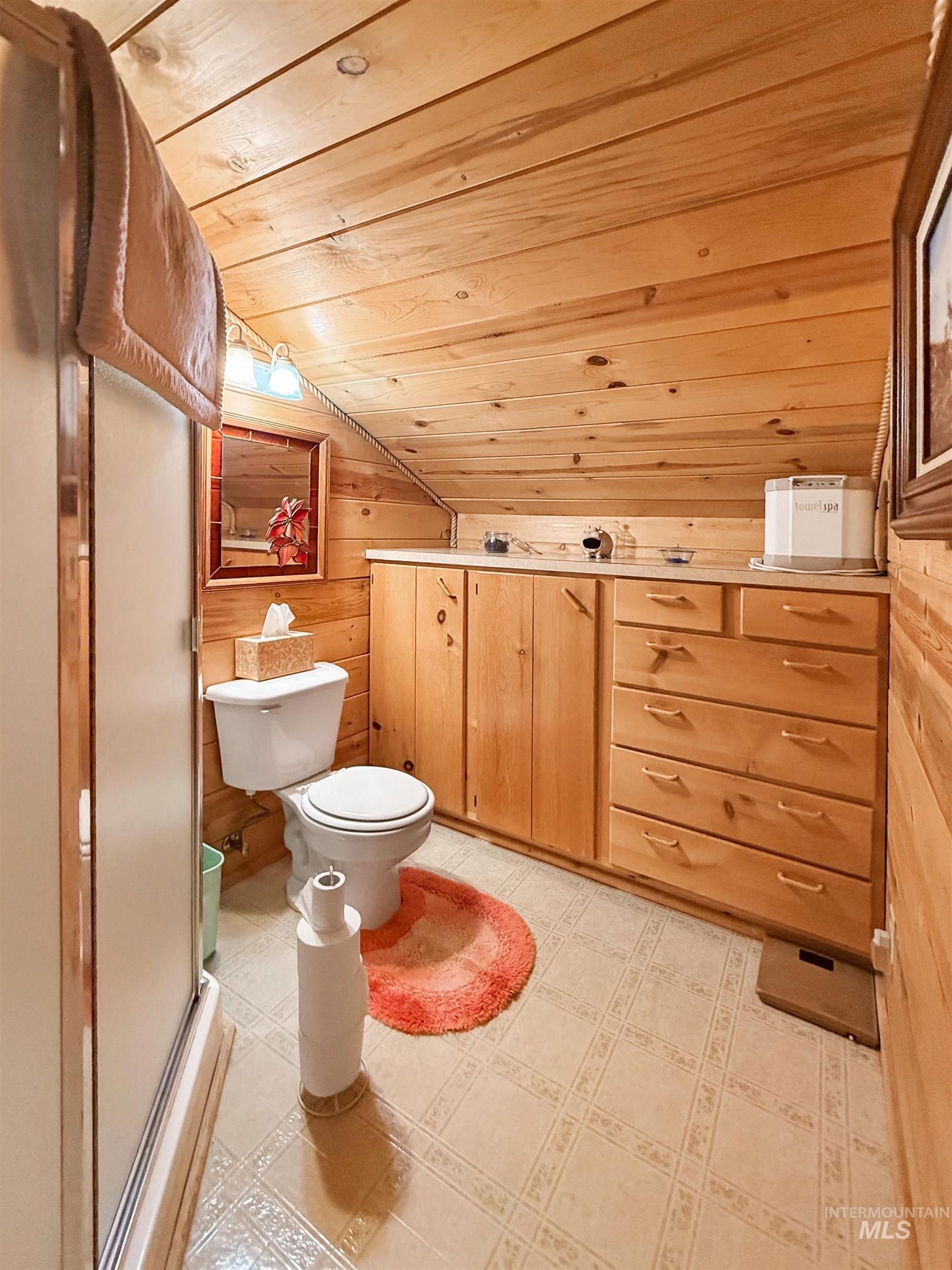 Full bath with wooden ceiling, lofted ceiling, and wooden walls