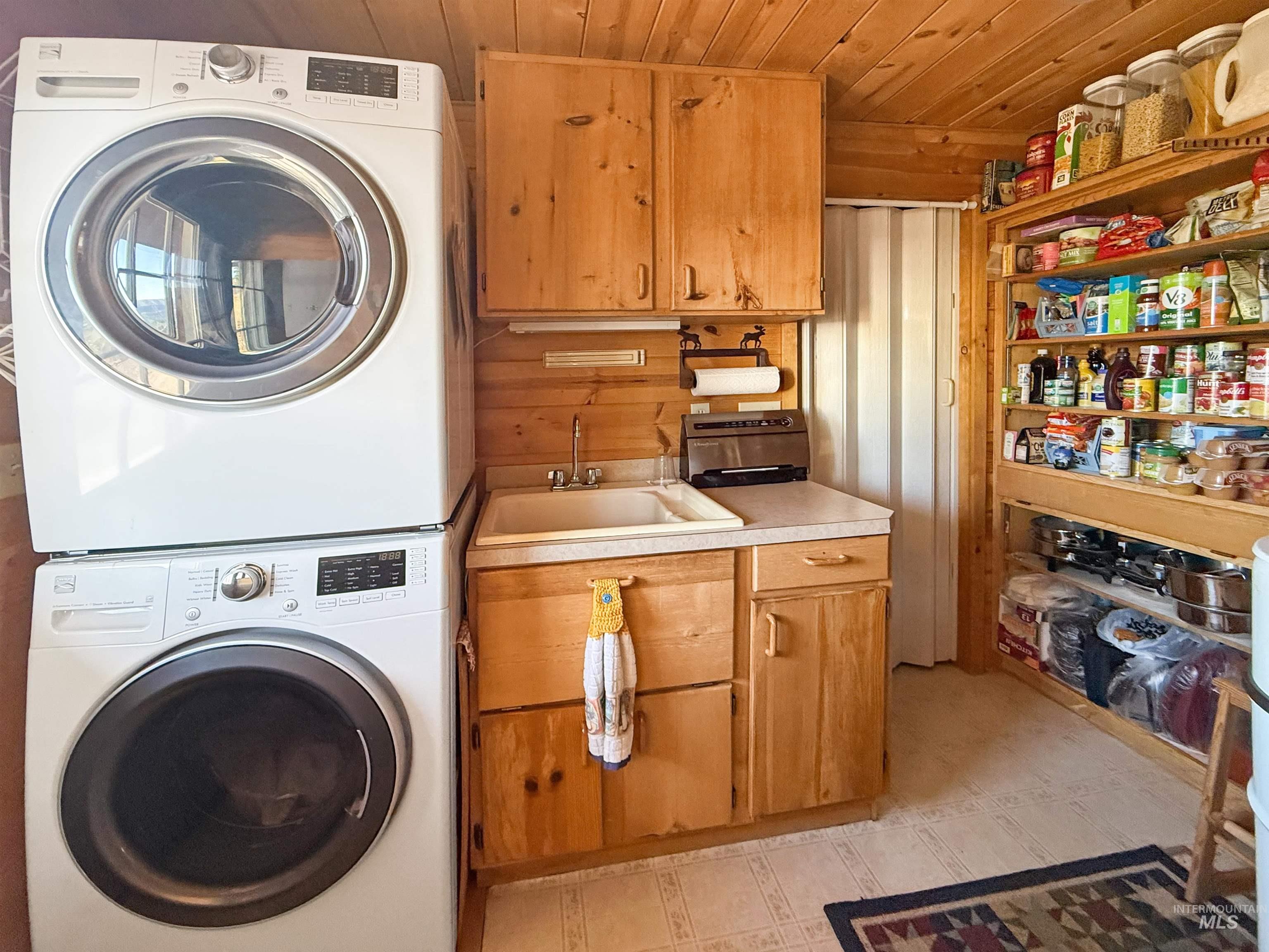 Laundry room featuring stacked washer / dryer, cabinet space, and wooden ceiling