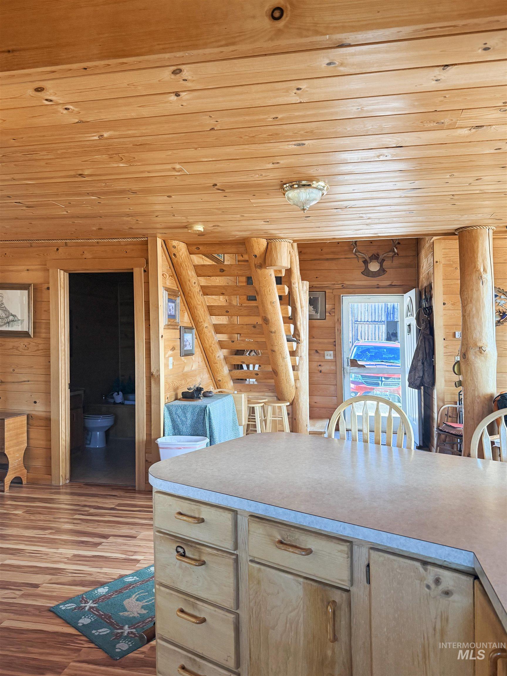 Kitchen featuring wooden ceiling, wood walls, wood finished floors, light countertops, and light brown cabinets
