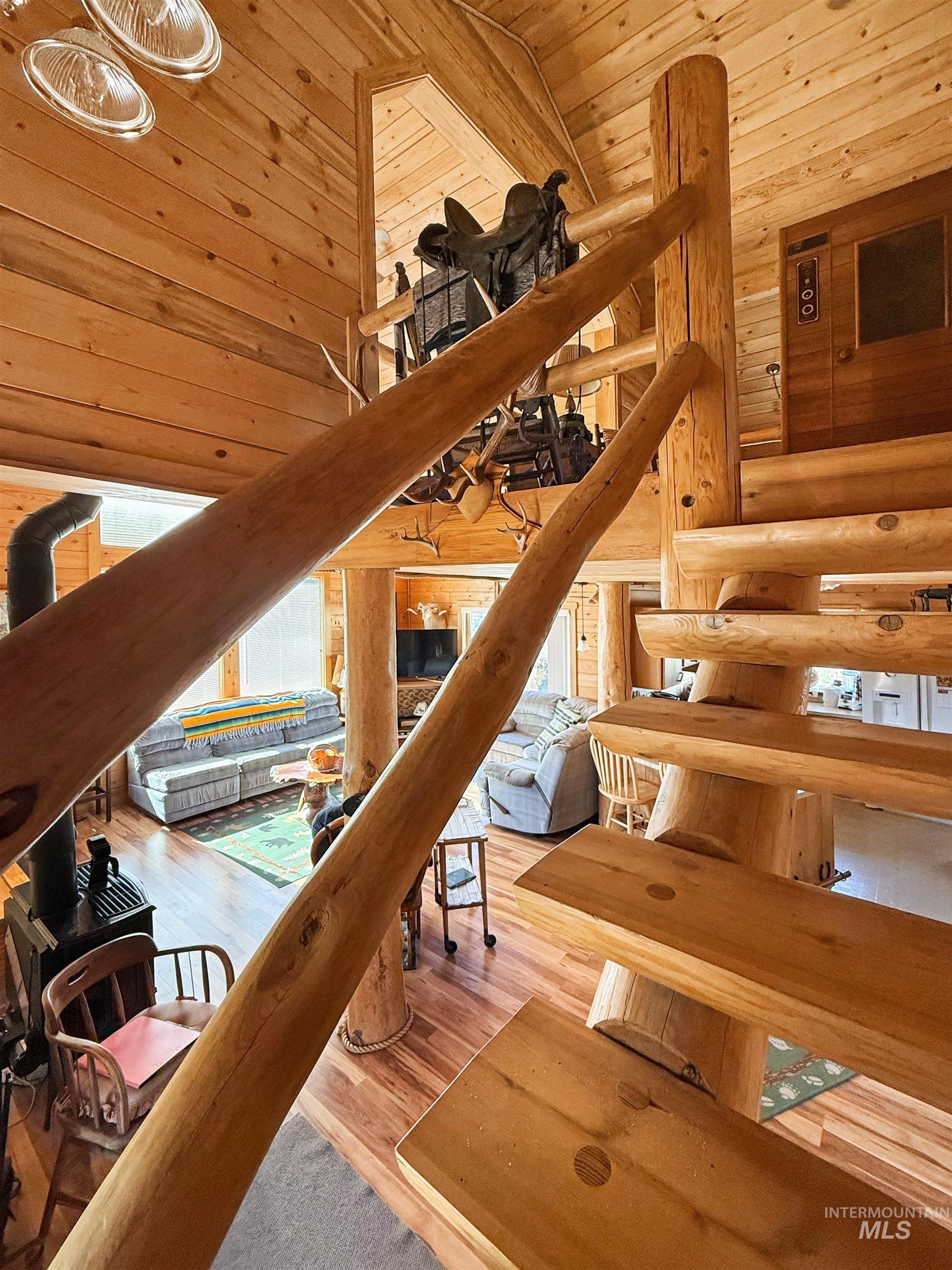 Staircase with high vaulted ceiling, wooden ceiling, wood finished floors, rustic walls, and wood walls