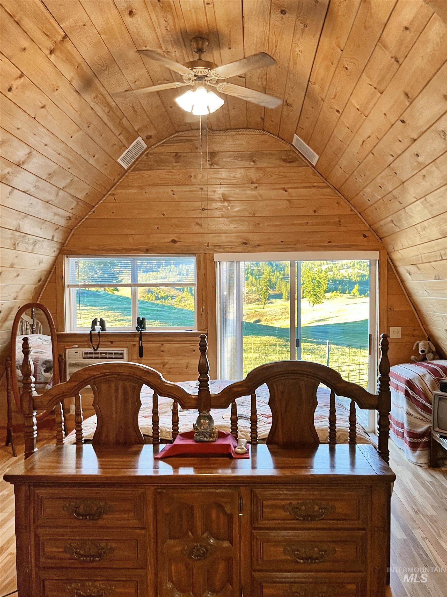 Dining area with light wood finished floors, wooden ceiling, lofted ceiling, wood walls, and a ceiling fan