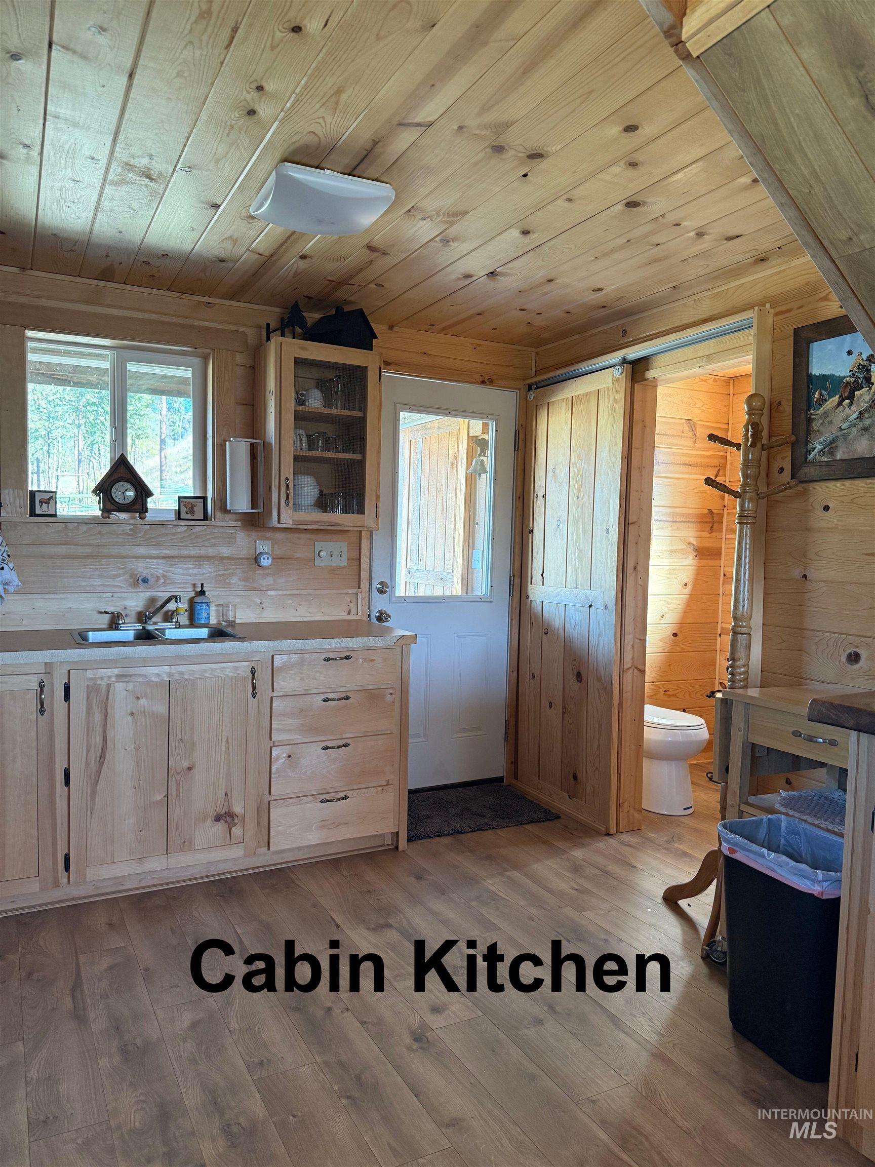 Kitchen featuring wood walls, light wood-style flooring, wood ceiling, light countertops, and light brown cabinets