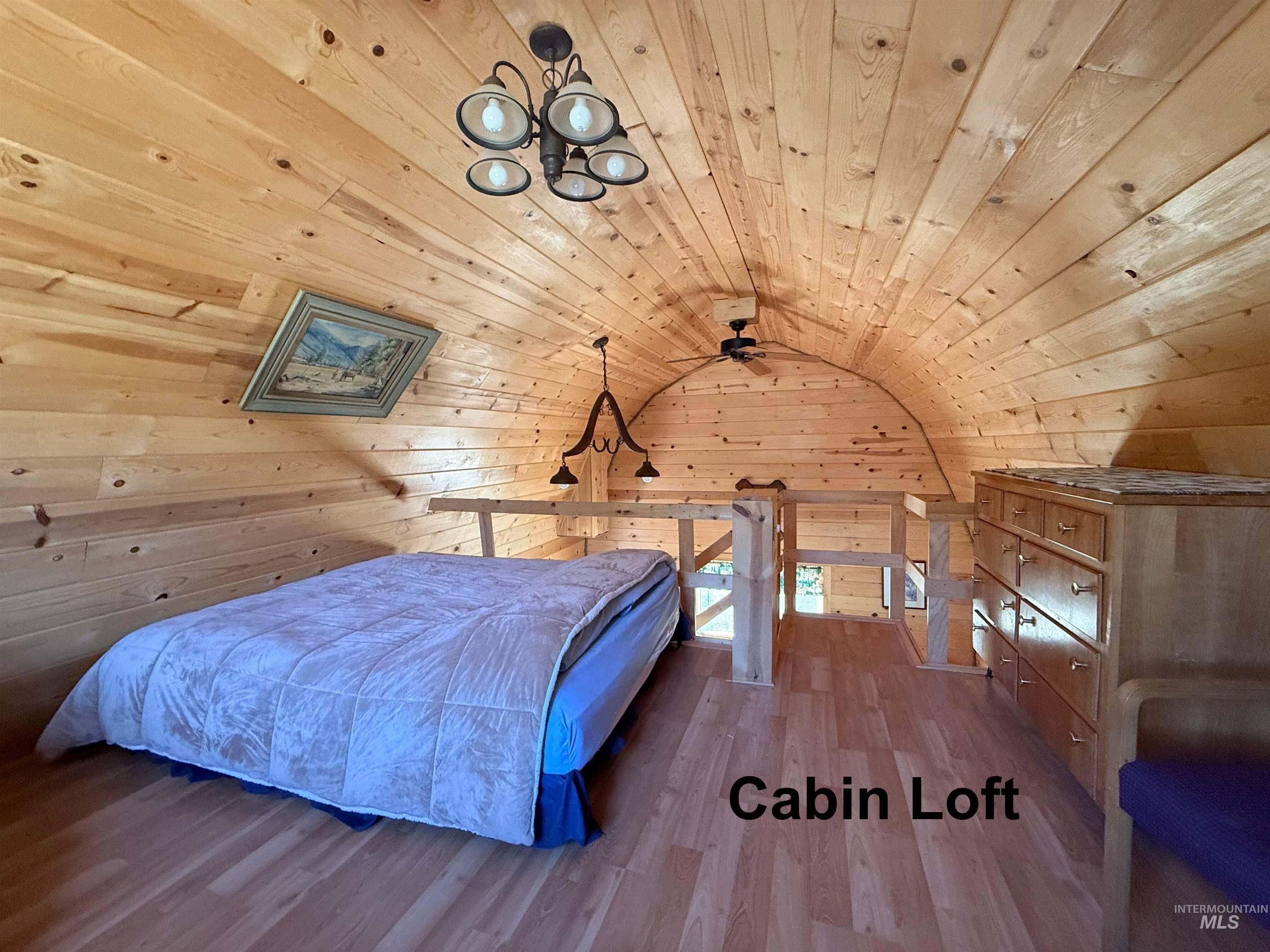 Bedroom with wood finished floors, vaulted ceiling, wood walls, and wood ceiling