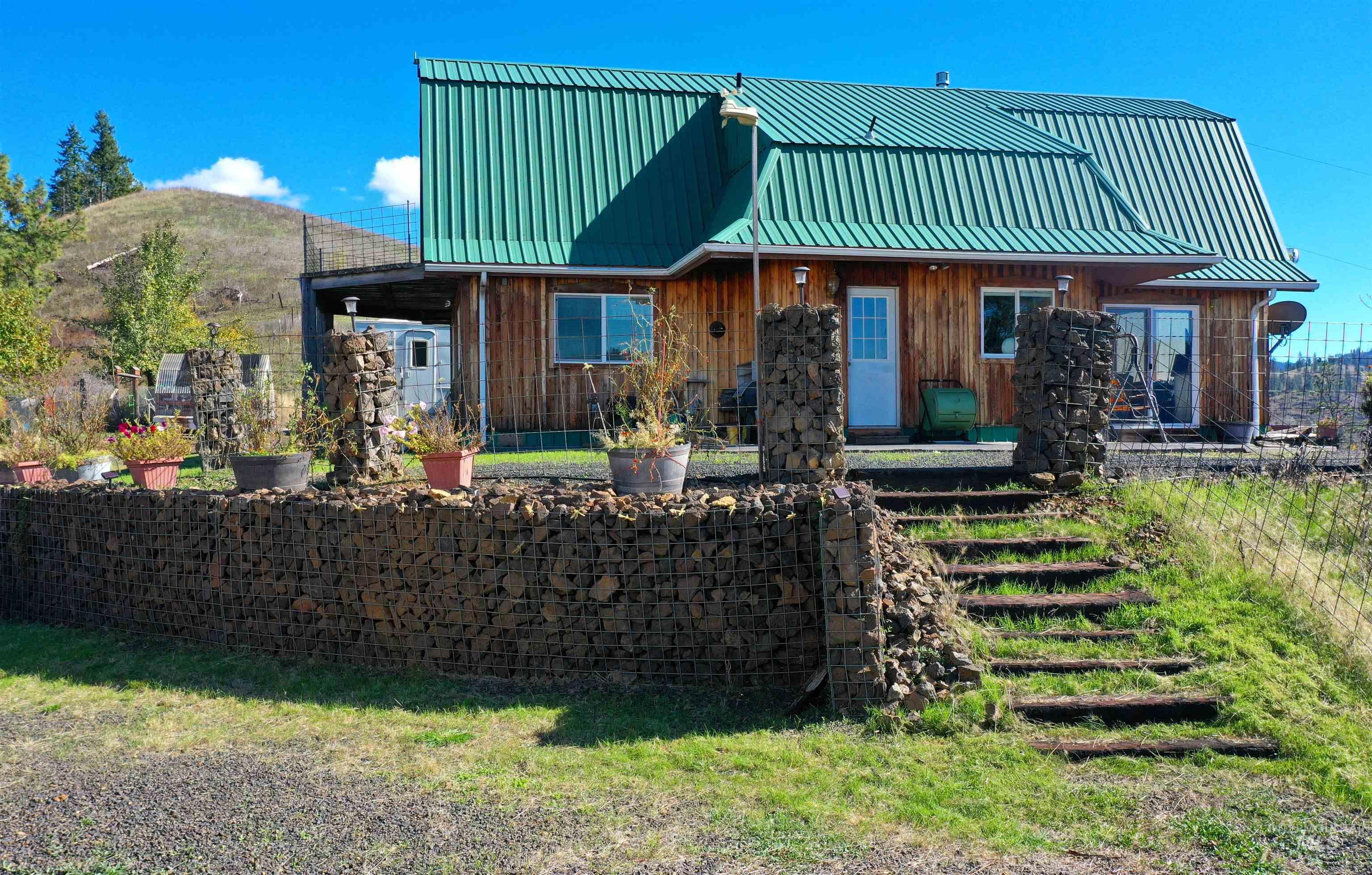 Back of property featuring covered porch, a gambrel roof, a metal roof, and board and batten siding