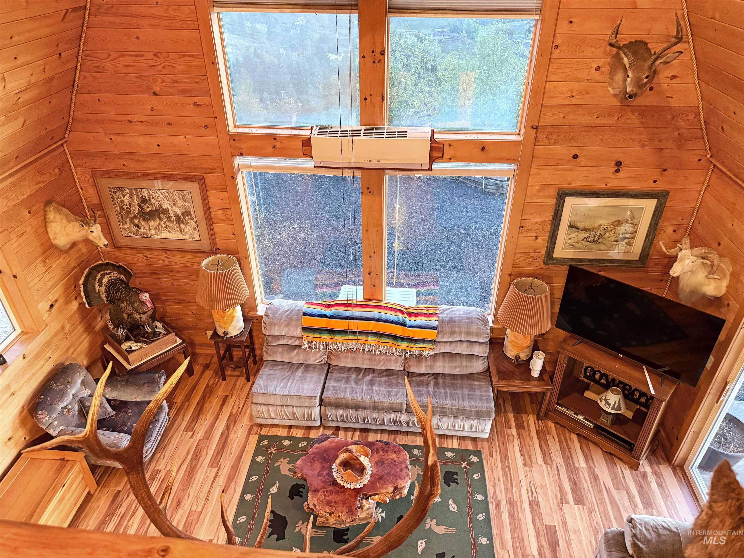 Living area featuring wood finished floors, wooden walls, and a high ceiling