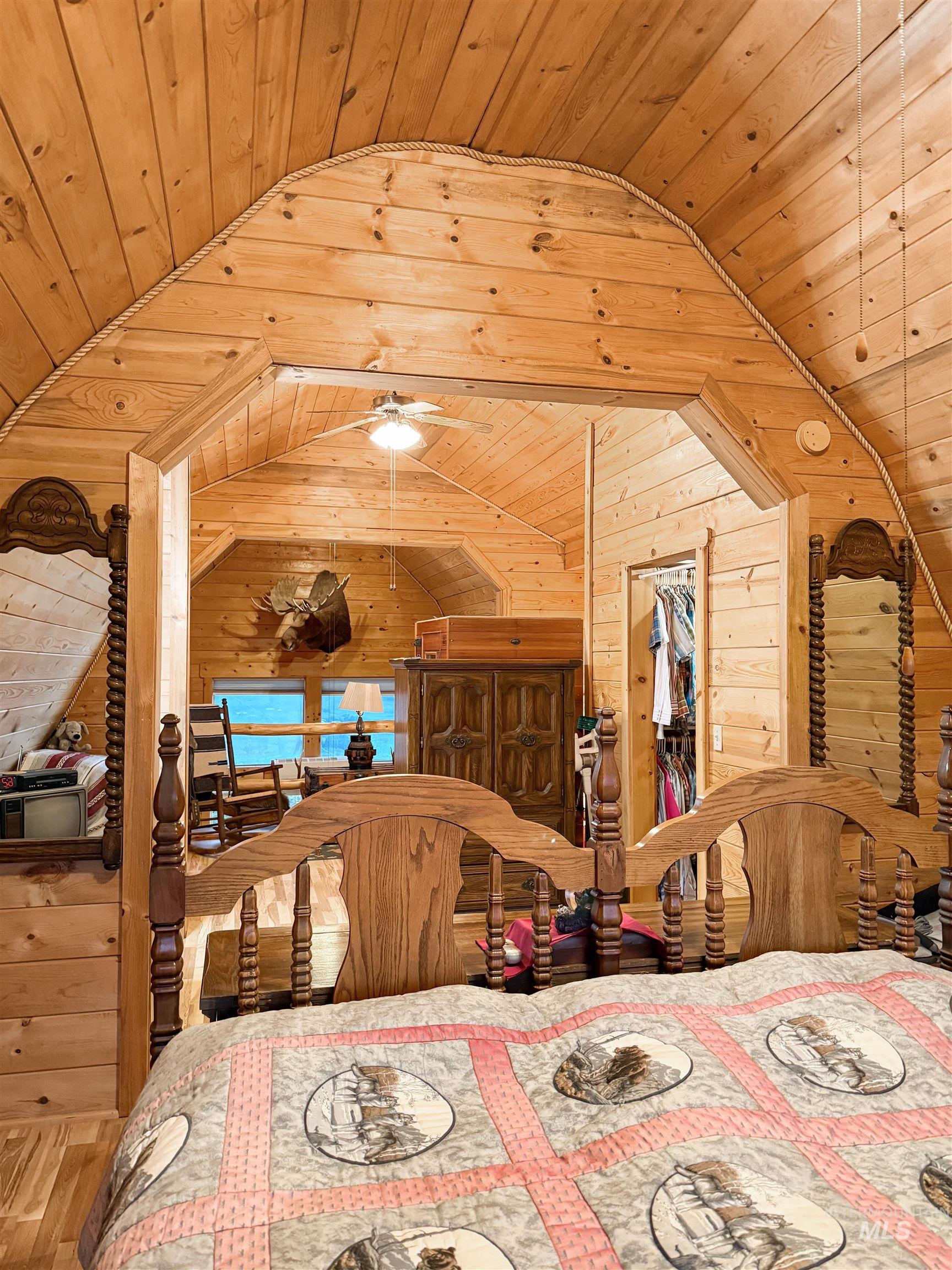 Bedroom featuring wooden ceiling, wood walls, and vaulted ceiling