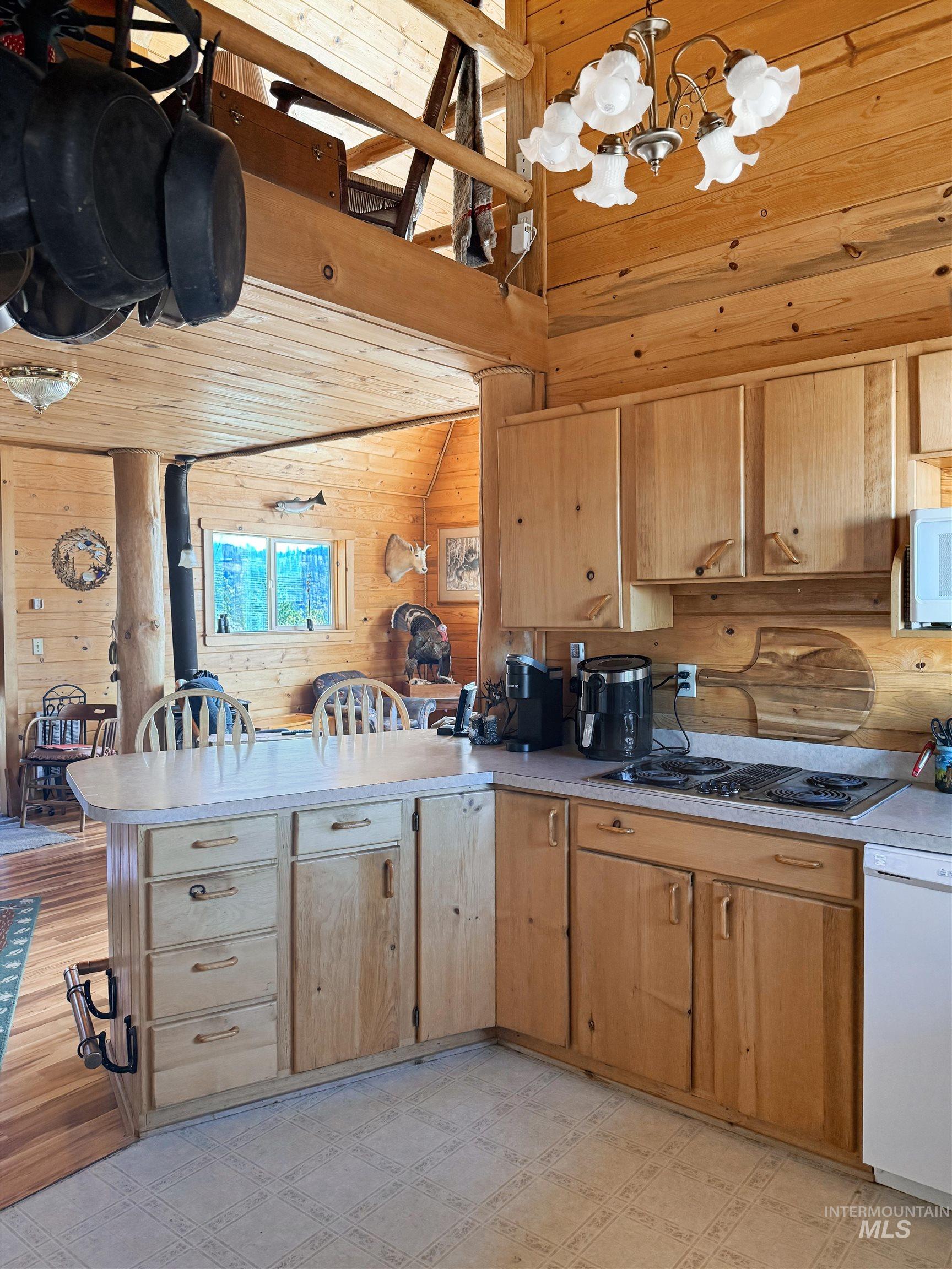 Kitchen with a peninsula, light countertops, wood walls, vaulted ceiling, and wood ceiling