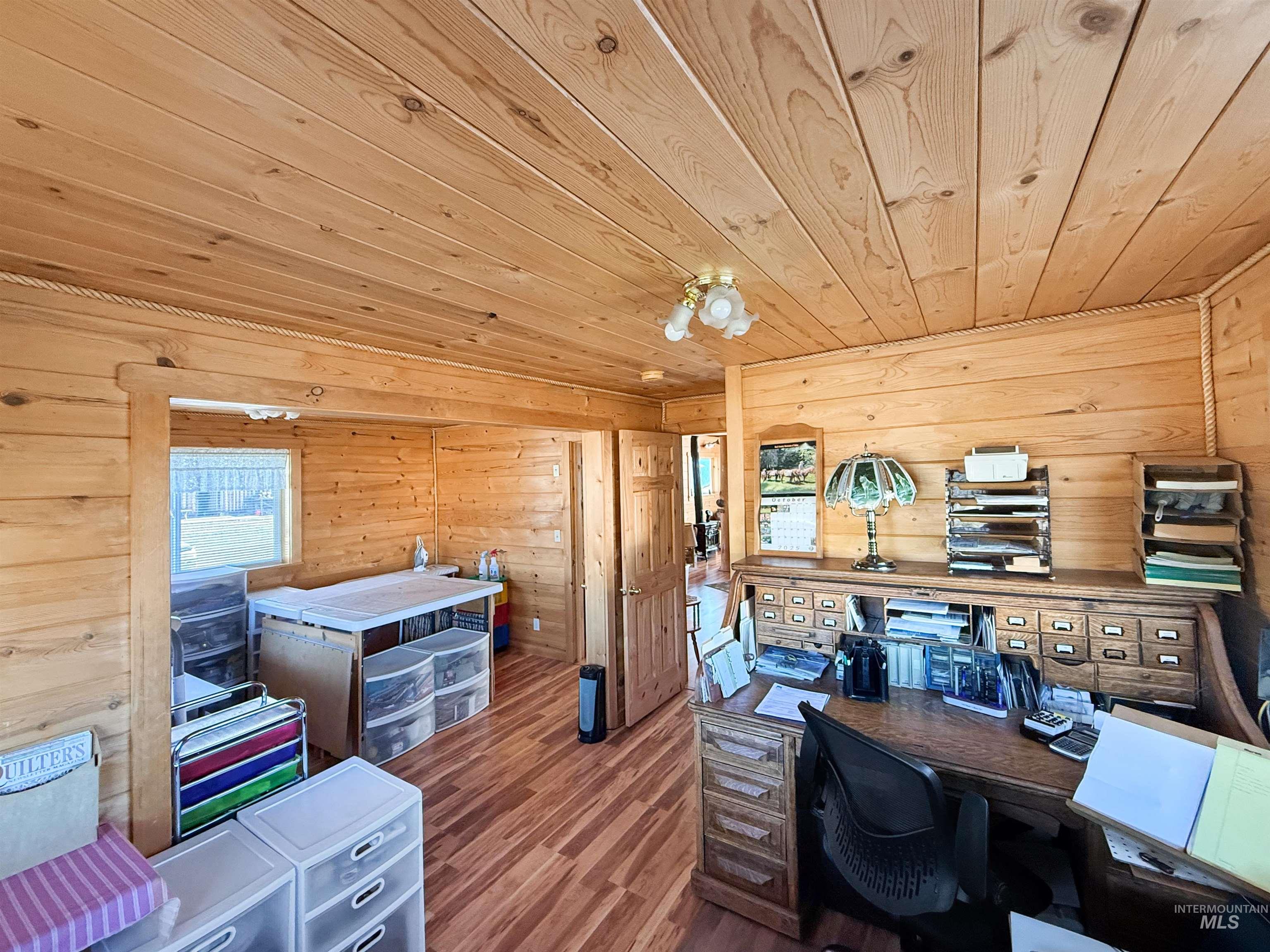 Office with dark wood-type flooring, wooden ceiling, and wood walls