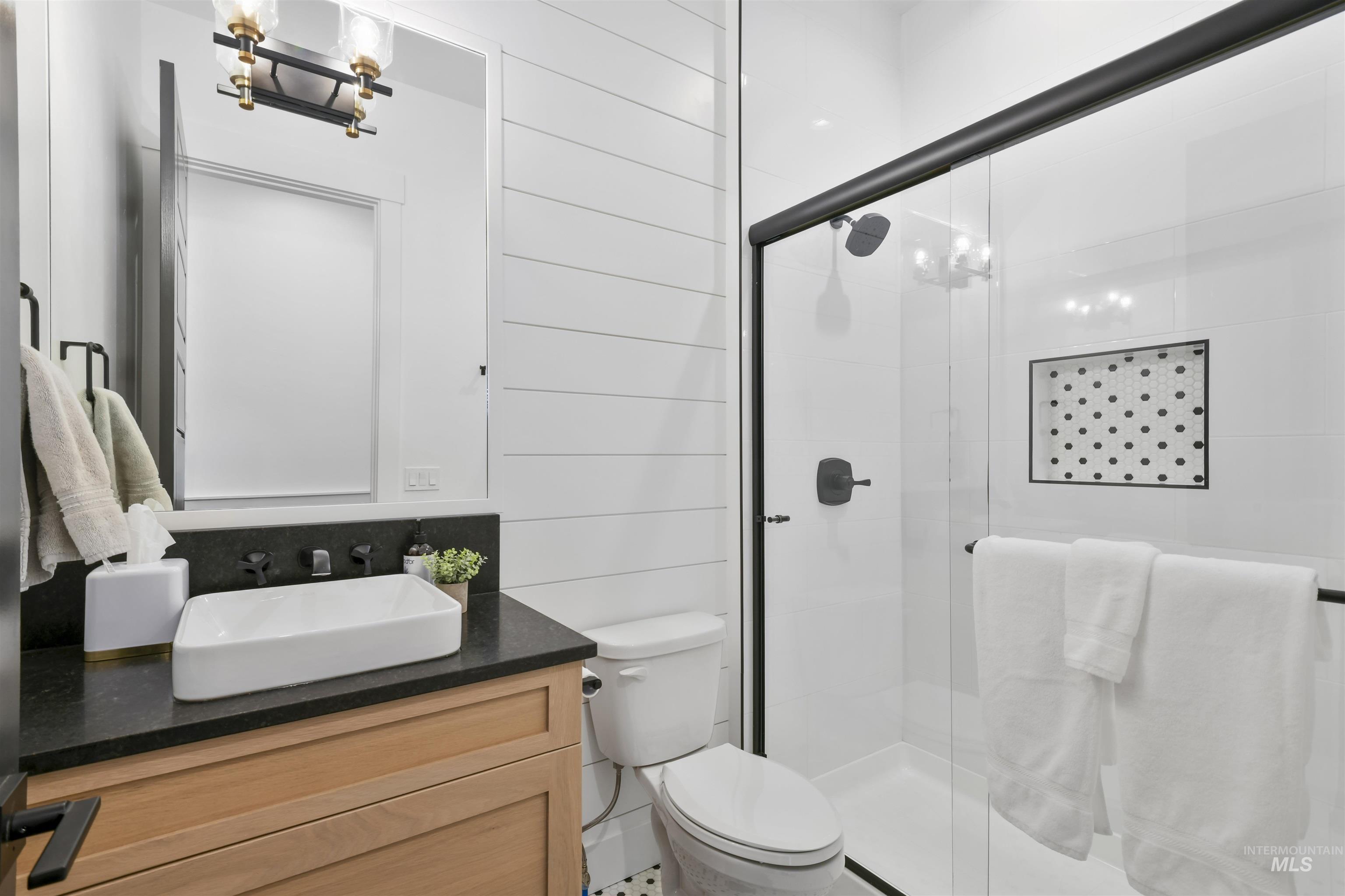 Full bath with vanity, a shower stall, and a chandelier