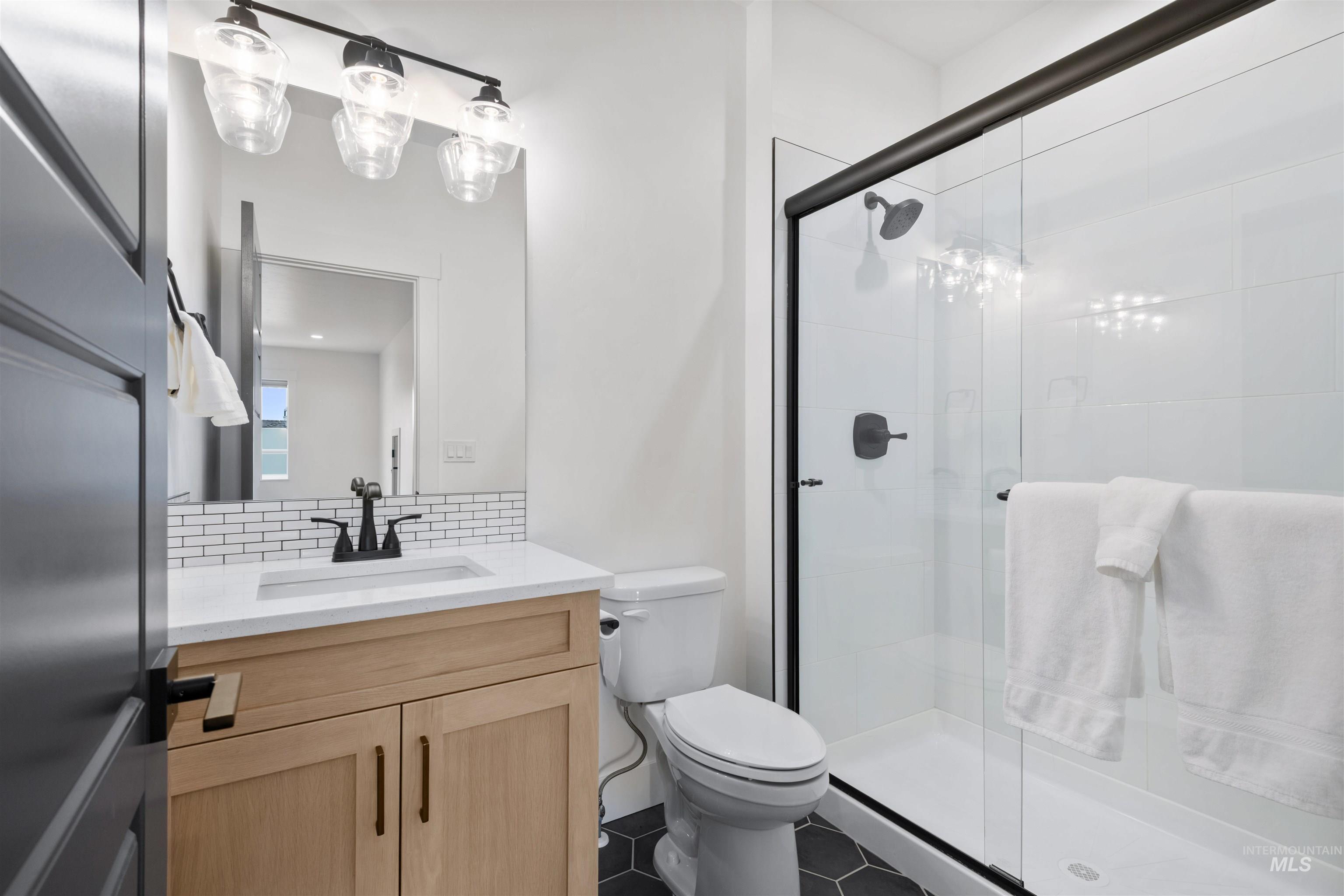 Bathroom with vanity, tasteful backsplash, and a stall shower