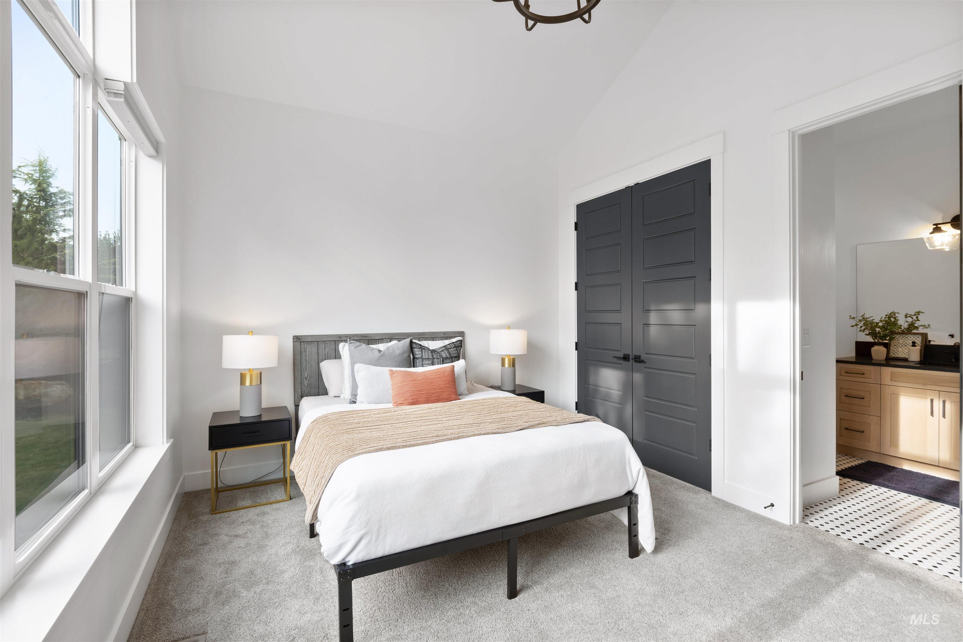 Bedroom with light colored carpet, a closet, ensuite bath, and high vaulted ceiling