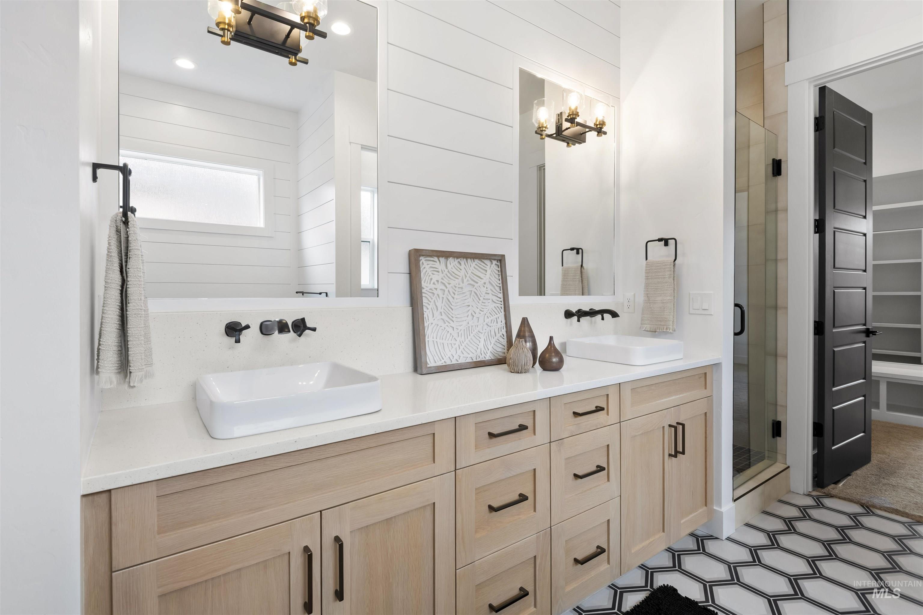 Bathroom with a chandelier, double vanity, a stall shower, wooden walls, and a spacious closet
