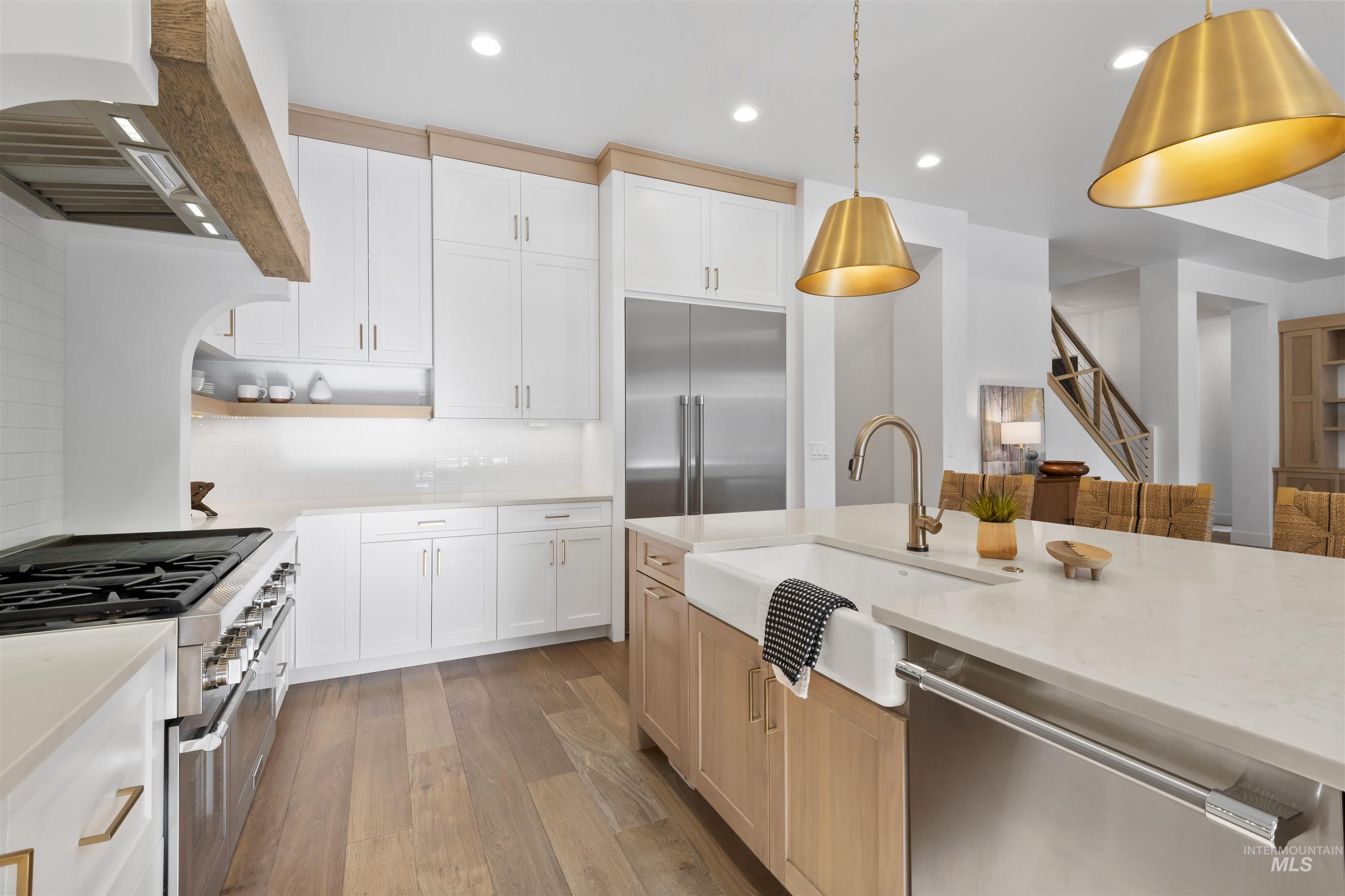 Kitchen featuring white cabinets, appliances with stainless steel finishes, light stone countertops, open shelves, and custom exhaust hood