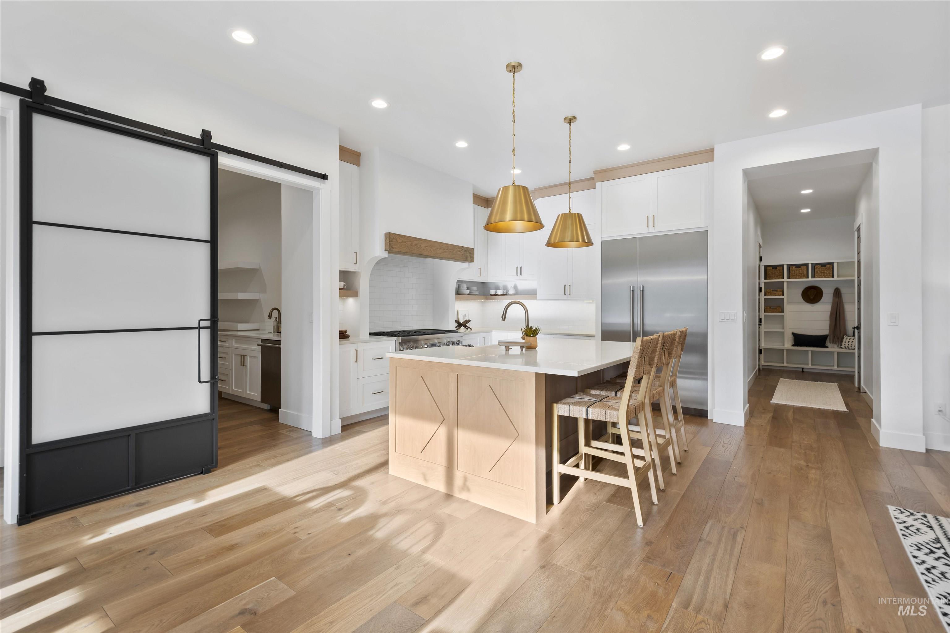 Kitchen with a barn door, decorative light fixtures, appliances with stainless steel finishes, white cabinets, and recessed lighting
