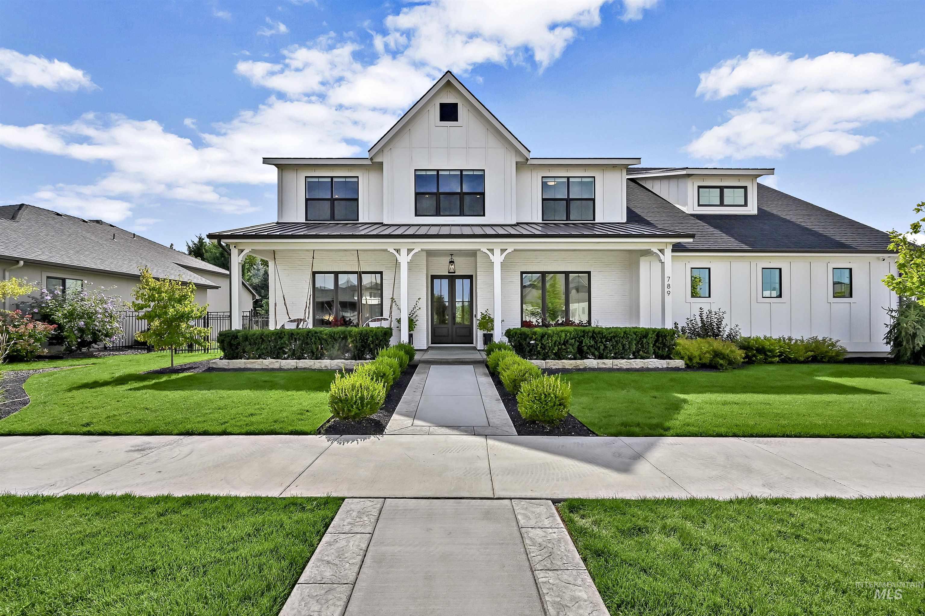 Modern farmhouse style home with a front yard, a porch, board and batten siding, and a metal roof