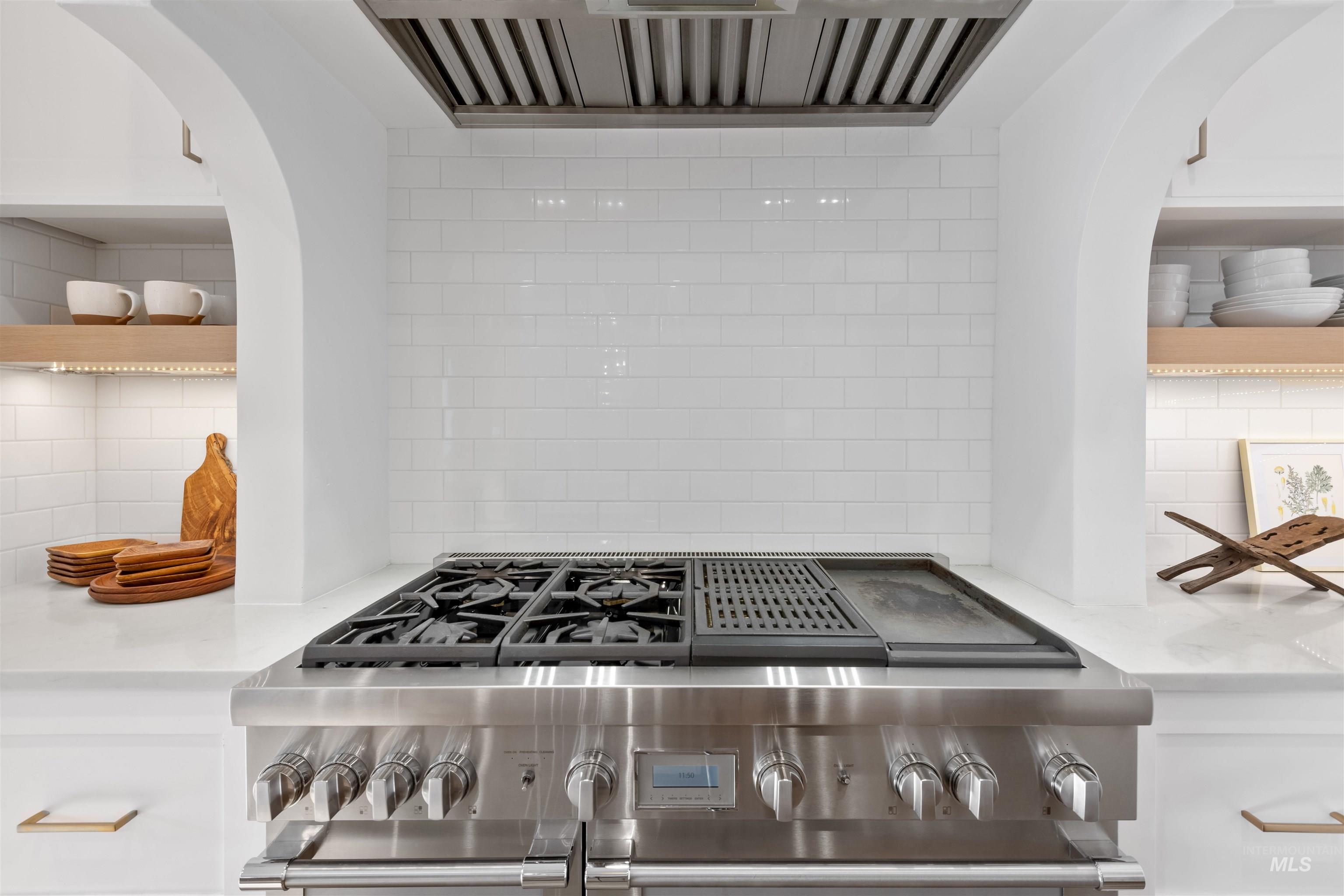 Kitchen view of arched walkways, range hood, and decorative backsplash
