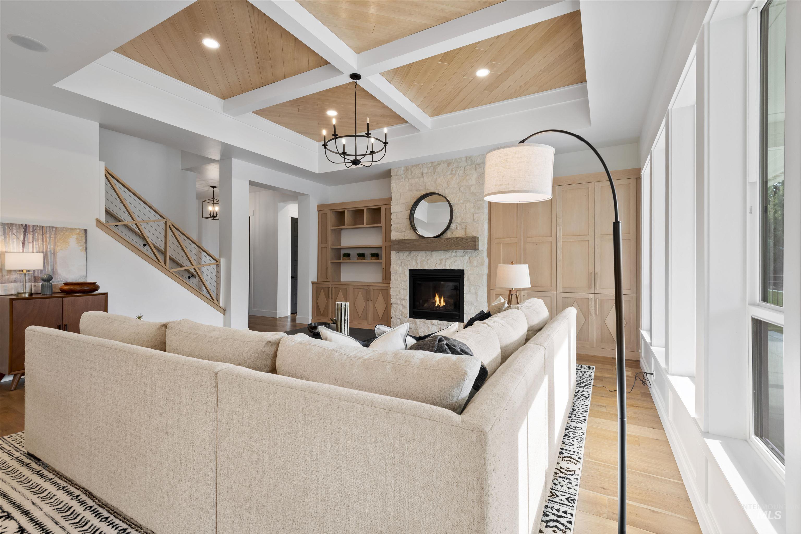 Living room with a wooden ceiling with exposed beams, a fireplace, wood finished floors, a chandelier, and coffered ceiling