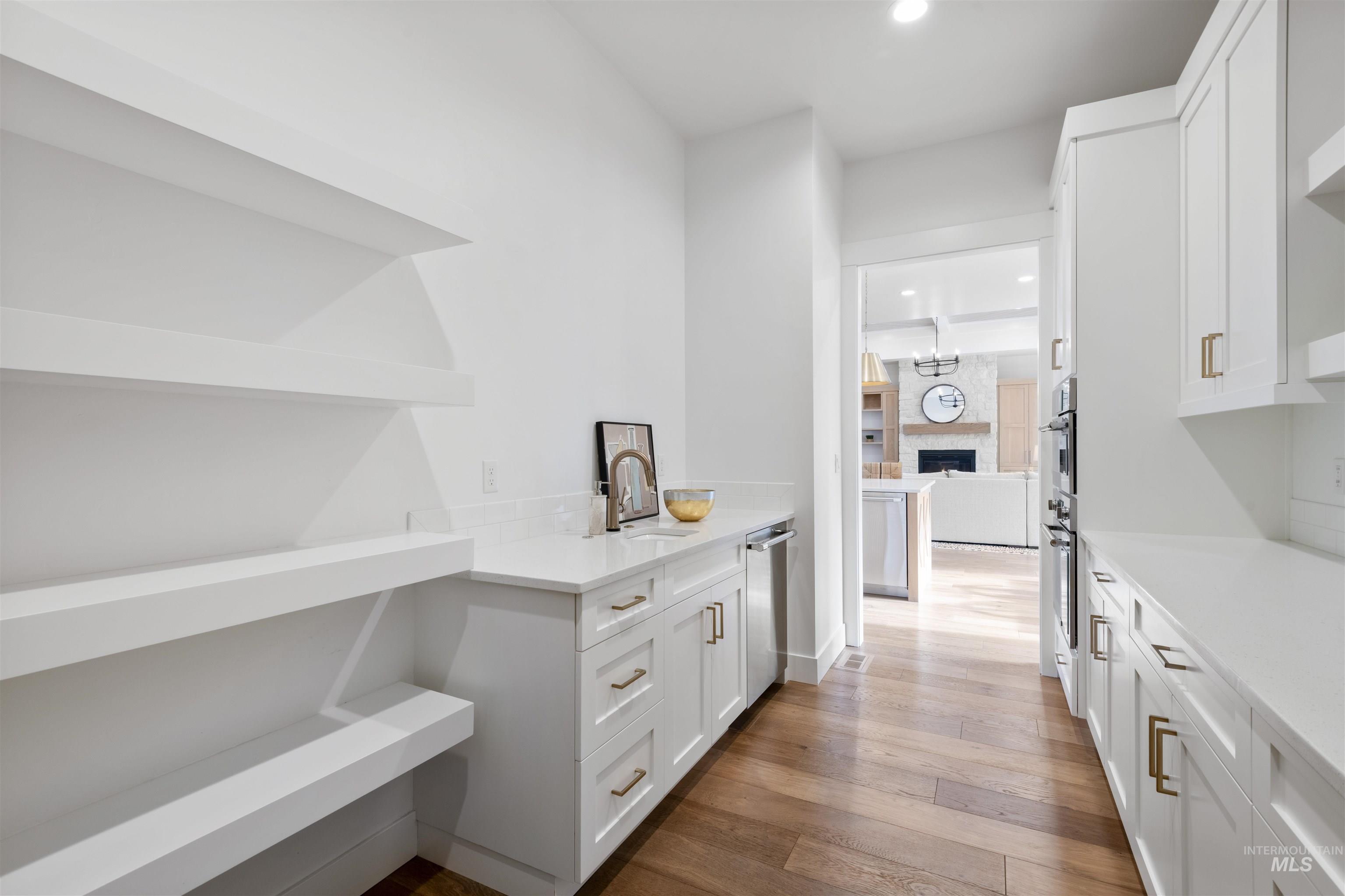 Bar featuring open shelves, white cabinets, light wood-type flooring, light stone counters, and a fireplace