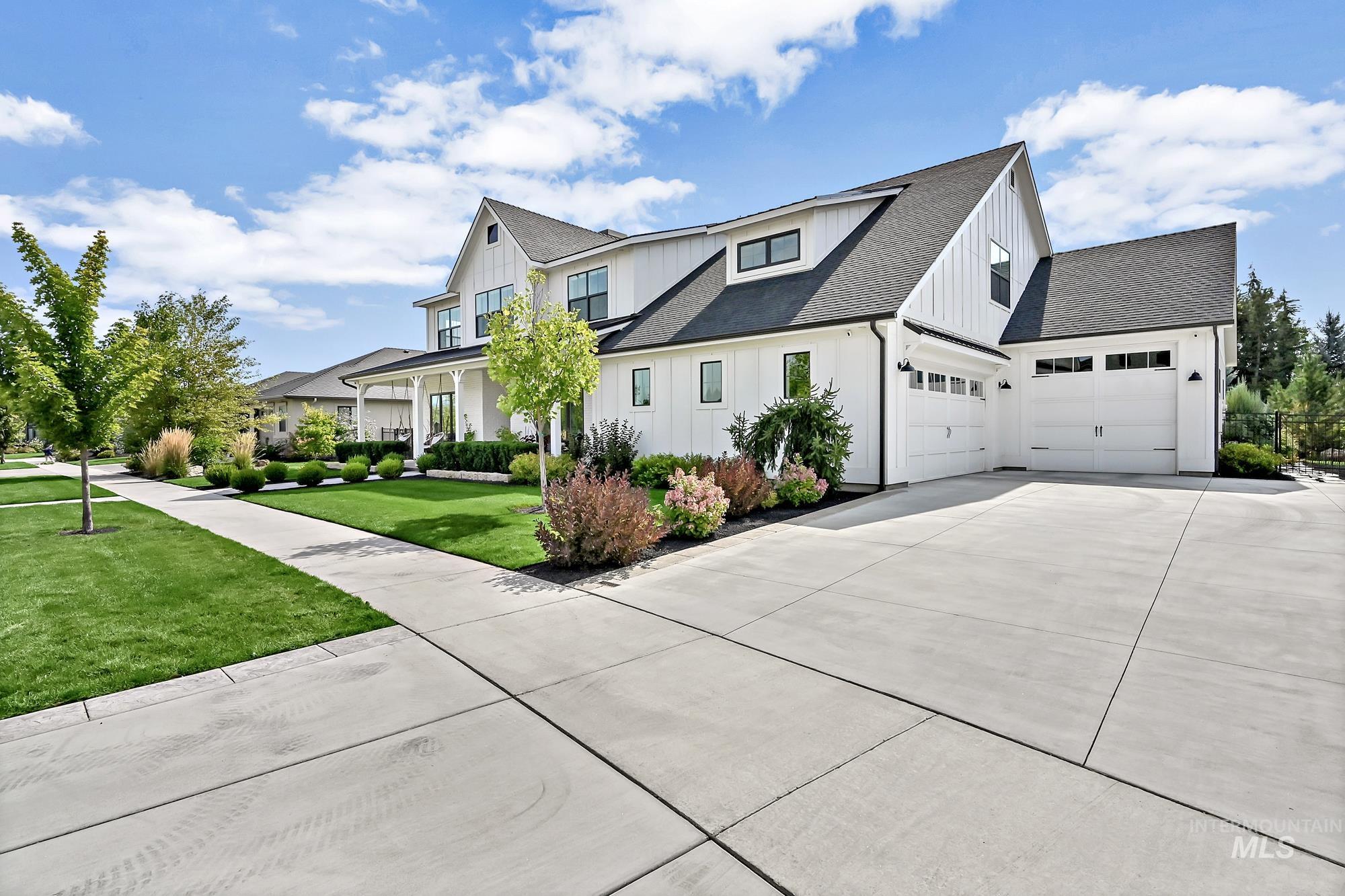 View of property exterior with a shingled roof, board and batten siding, driveway, and a lawn