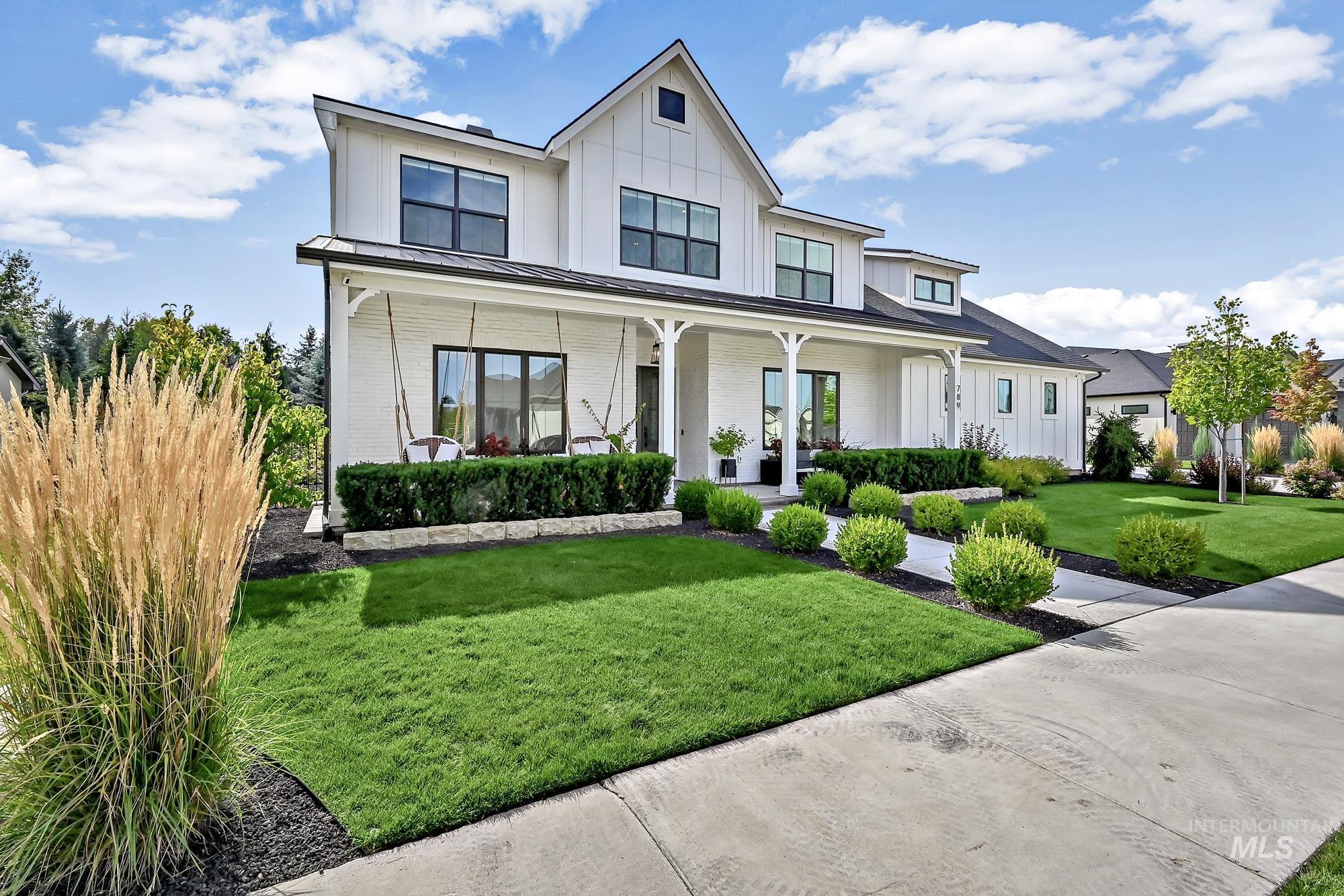 Modern farmhouse featuring brick siding, a standing seam roof, a porch, a metal roof, and a front yard