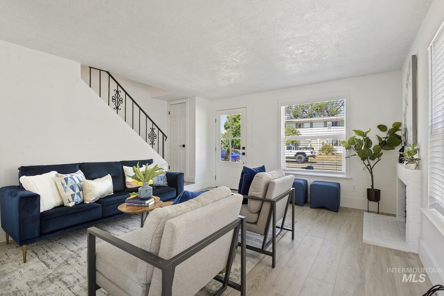Living room with wood finished floors, a textured ceiling, and stairway