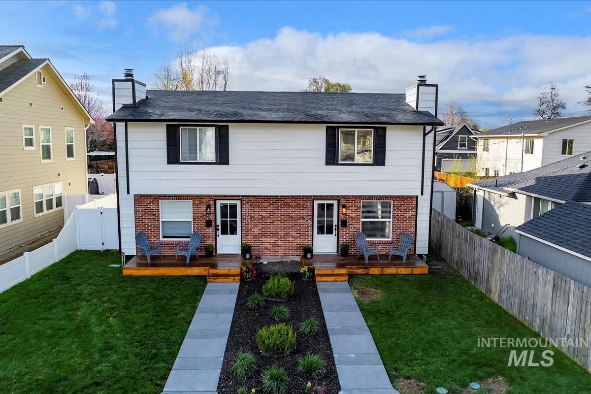 View of front of property with a chimney, a wooden deck, brick siding, and a fenced backyard