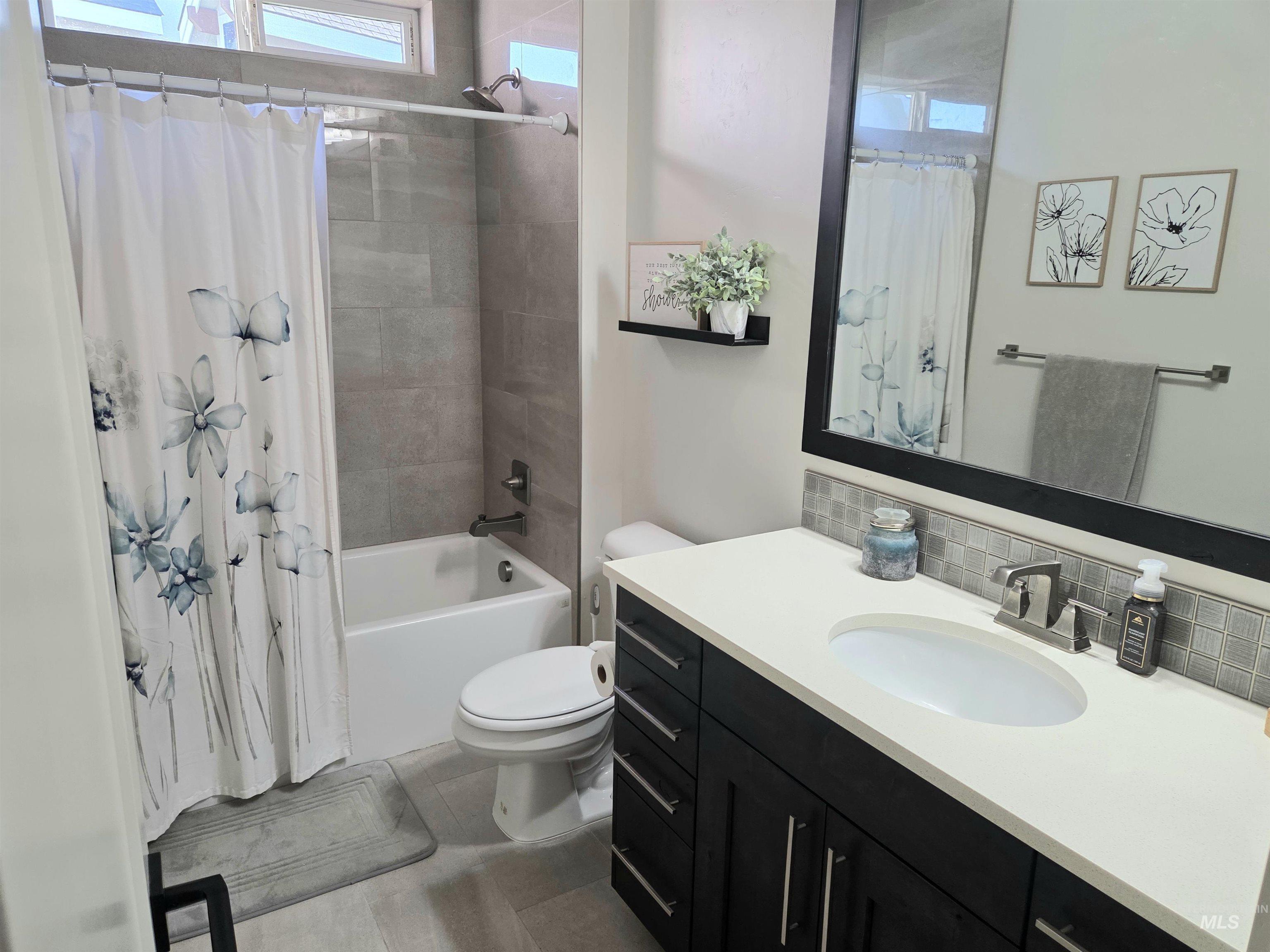 Full bathroom with vanity, backsplash, and shower / bath combo with shower curtain