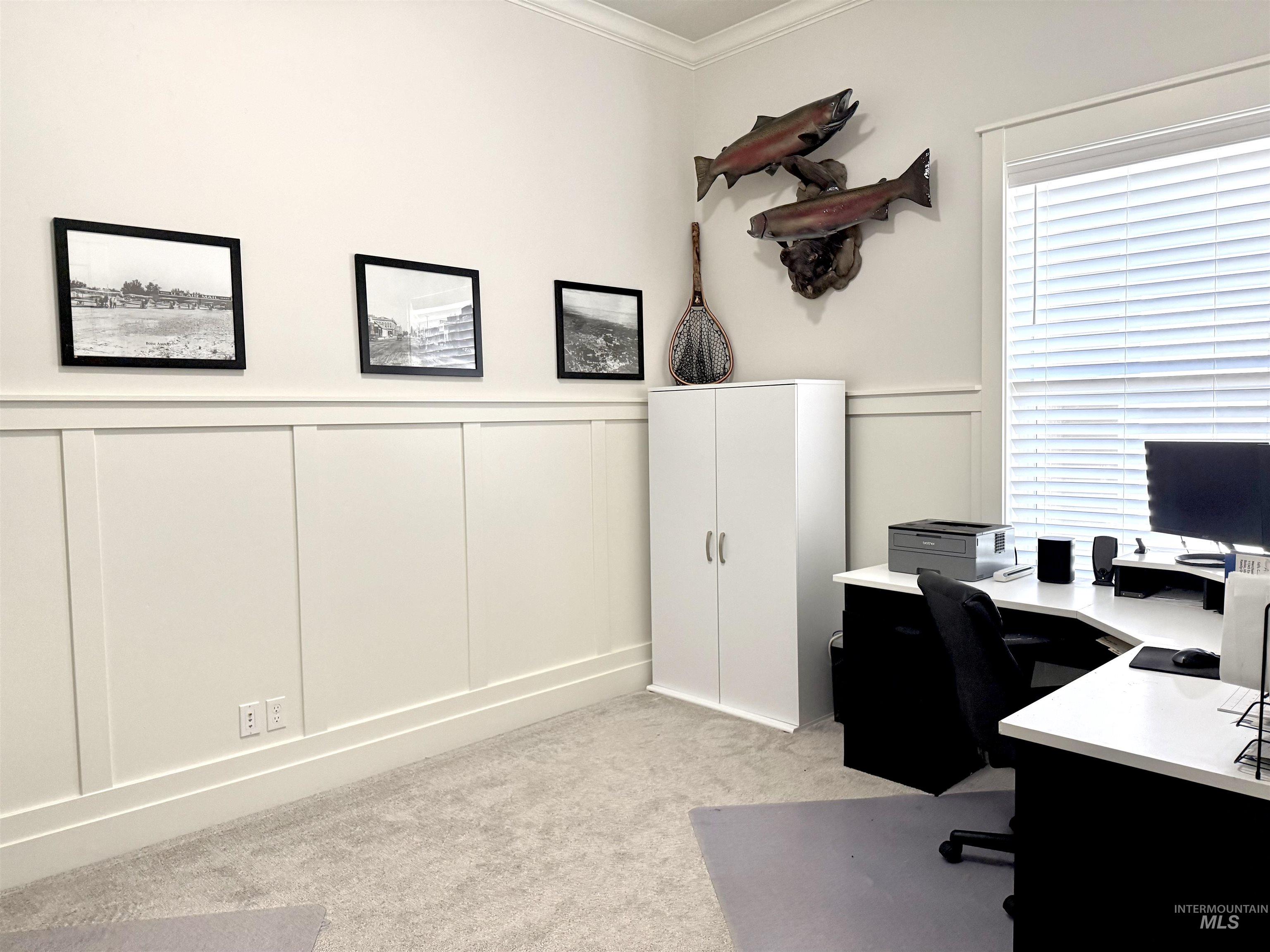 Office area with a decorative wall, wainscoting, crown molding, and light colored carpet