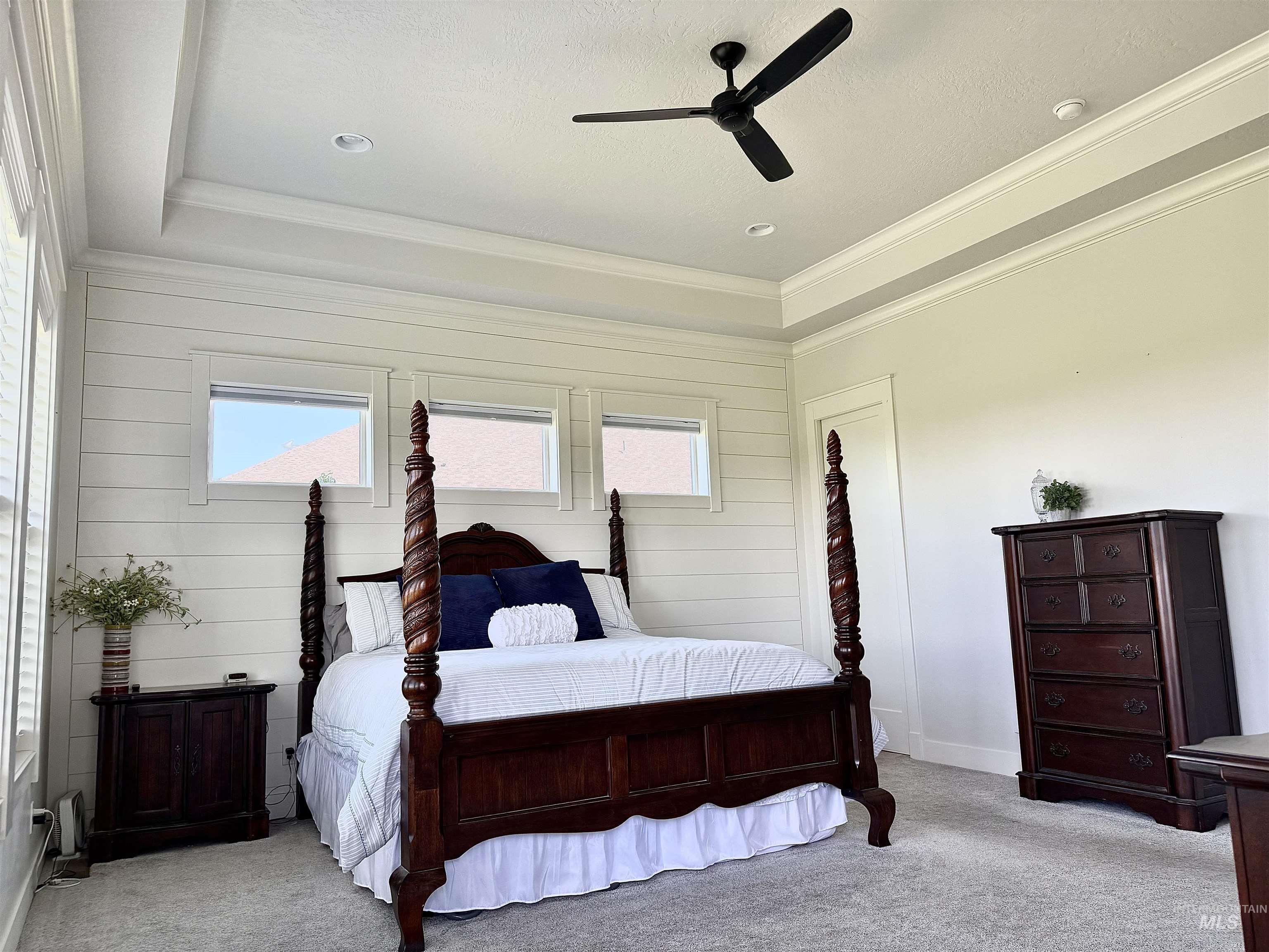 Bedroom featuring light carpet, ornamental molding, a ceiling fan, and wood walls
