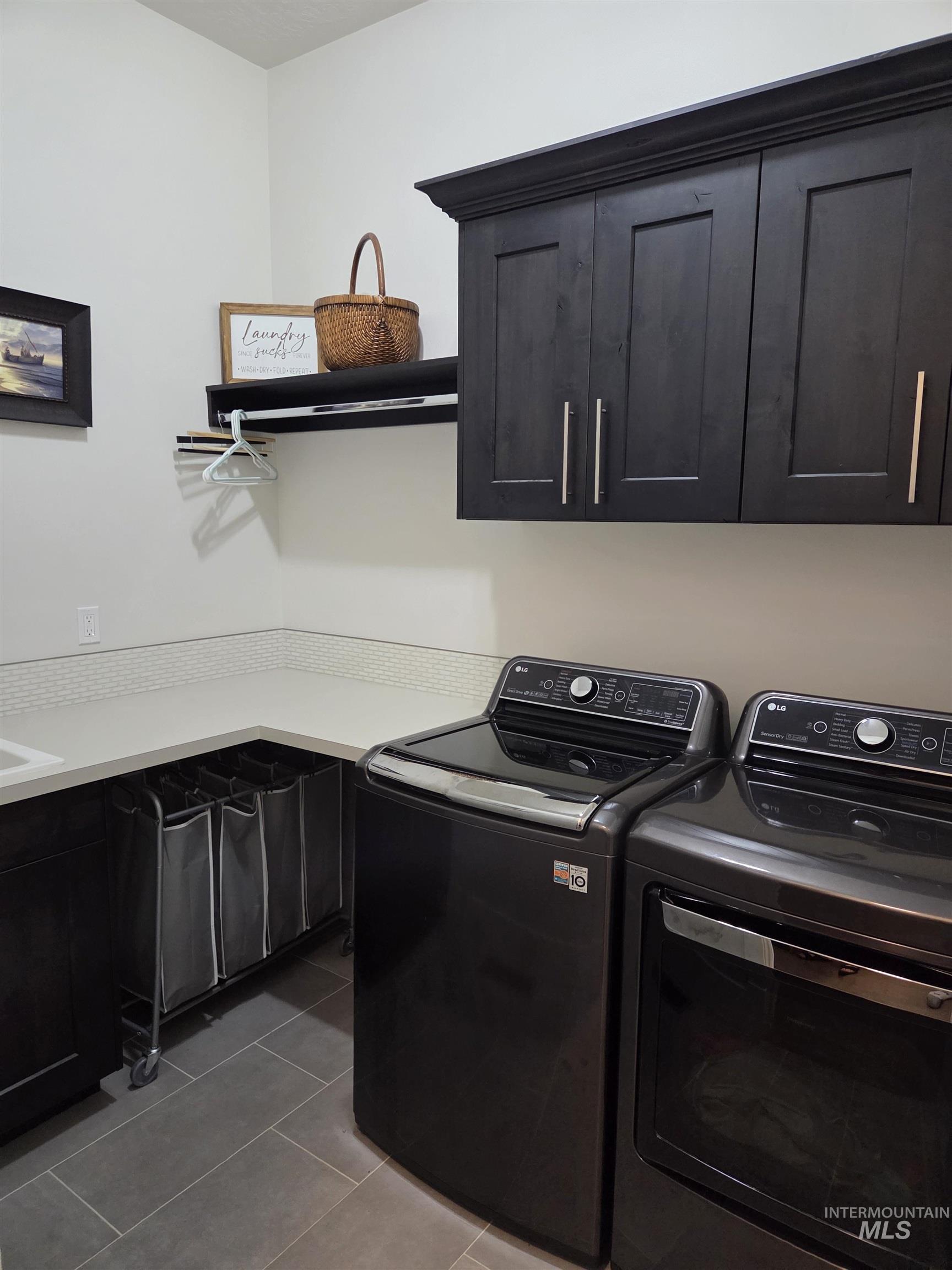 Laundry area featuring separate washer and dryer, cabinet space, and dark tile patterned floors