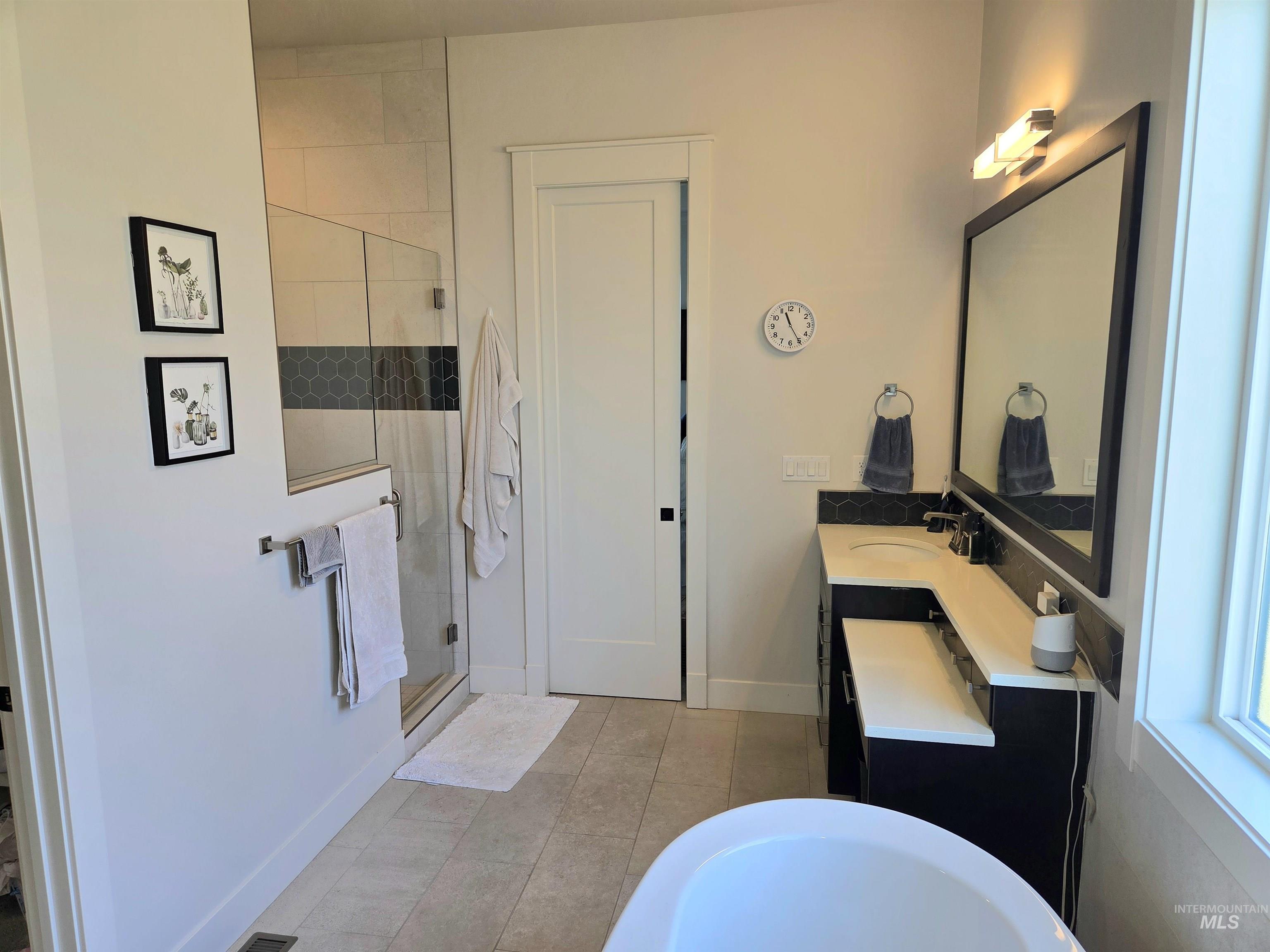 Bathroom featuring a shower stall, a freestanding bath, vanity, and tile patterned flooring