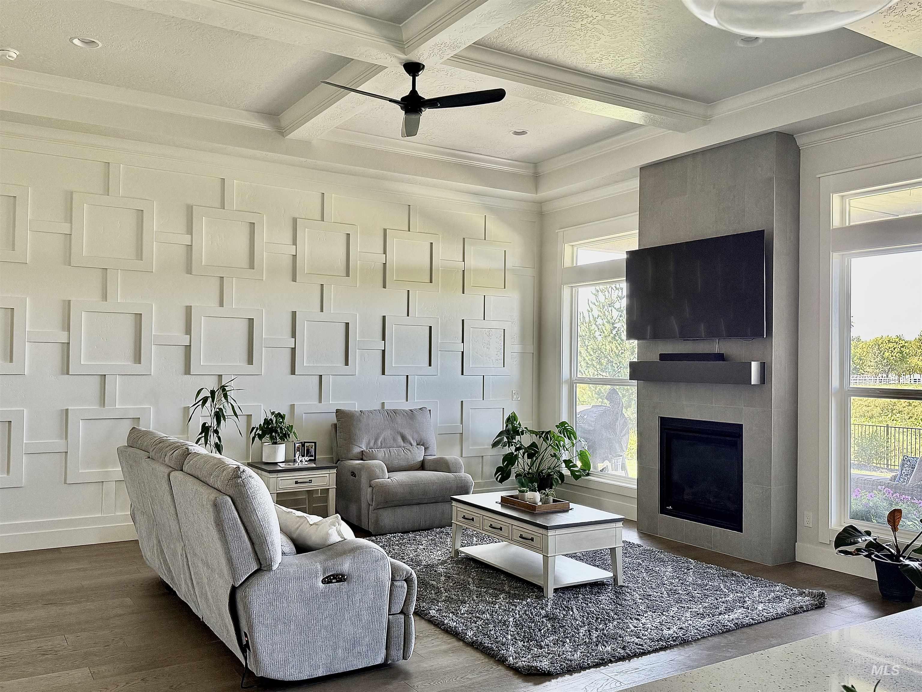 Living area with coffered ceiling, beamed ceiling, a fireplace, ceiling fan, and dark wood-type flooring