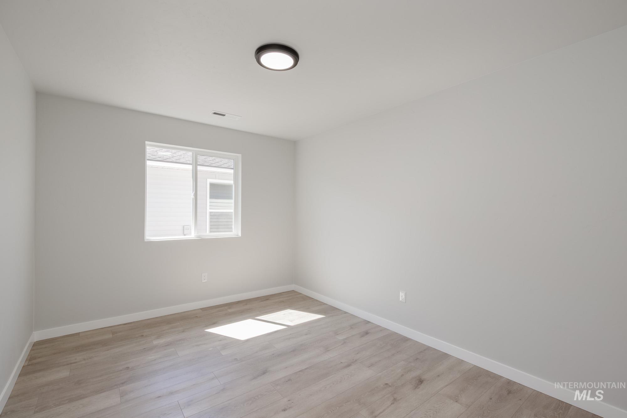 Empty room featuring baseboards and light wood finished floors