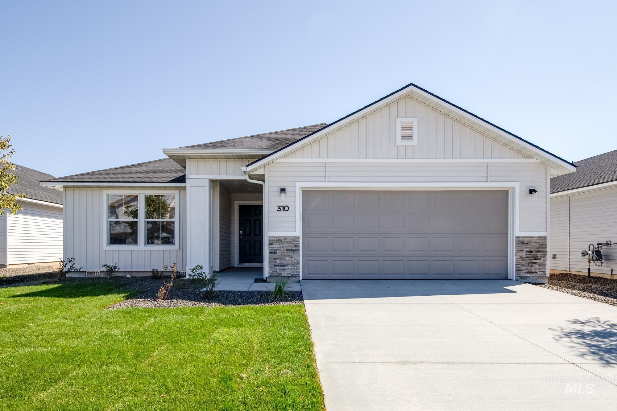 View of front of home with board and batten siding, roof with shingles, concrete driveway, and stone siding