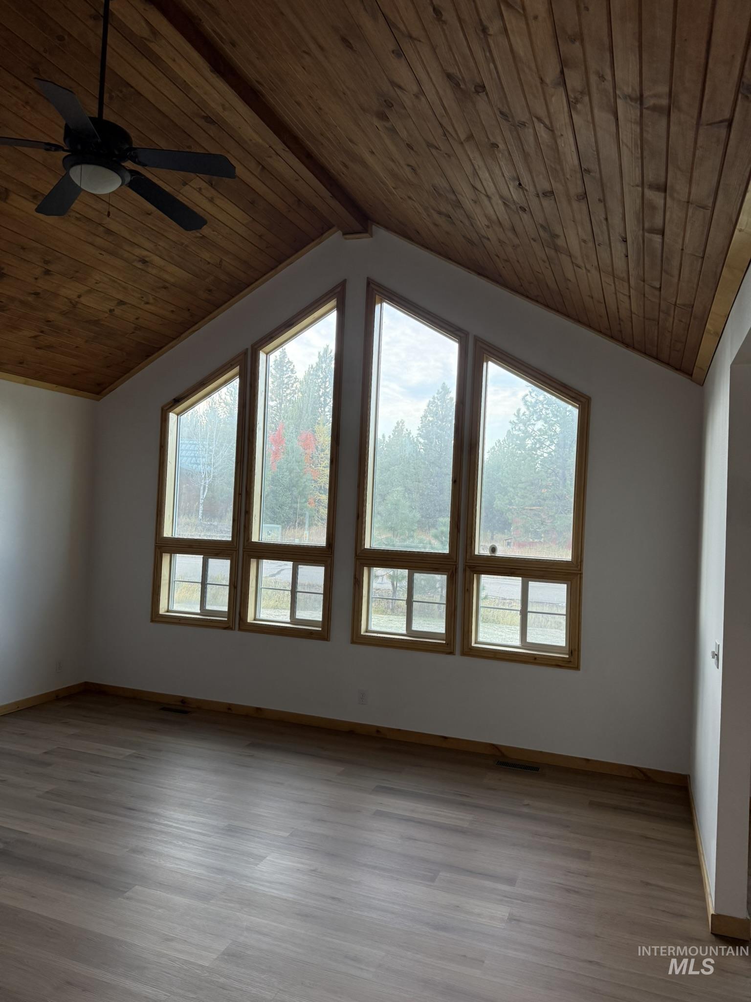 Unfurnished living room with healthy amount of natural light, light wood-style floors, wood ceiling, and a ceiling fan