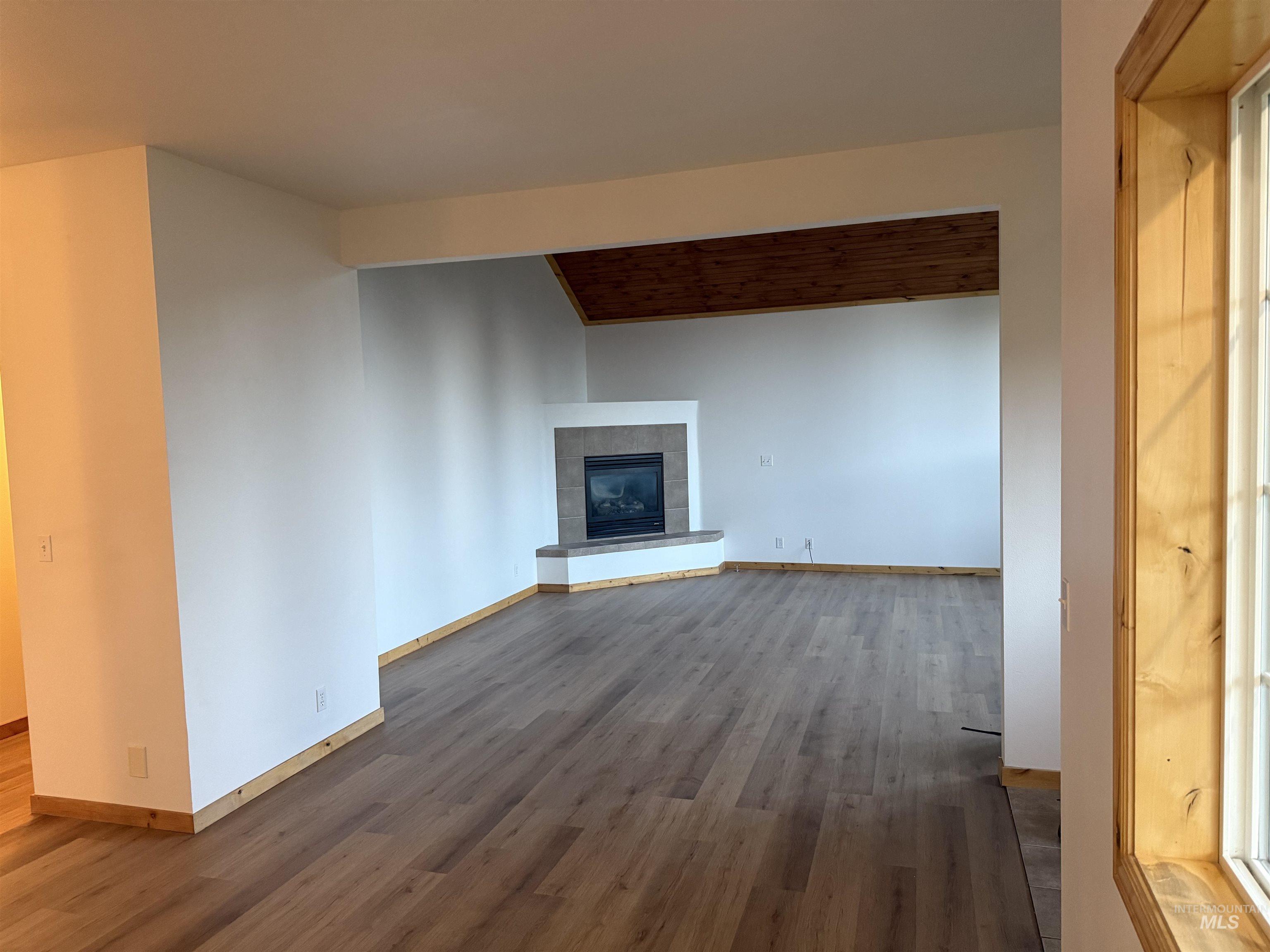 Unfurnished living room featuring dark wood-type flooring and a fireplace