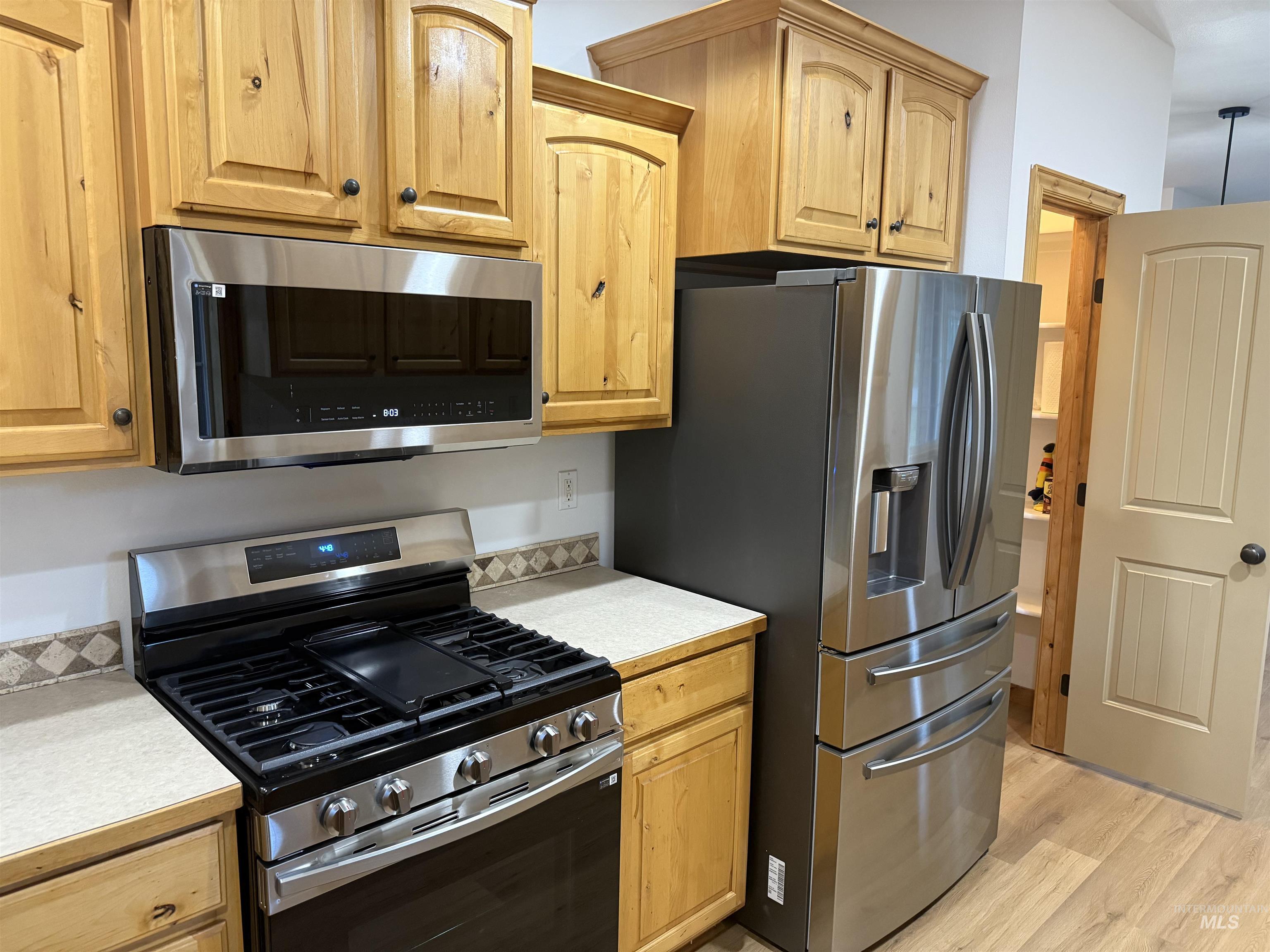 Kitchen with appliances with stainless steel finishes, light countertops, and light wood-style flooring