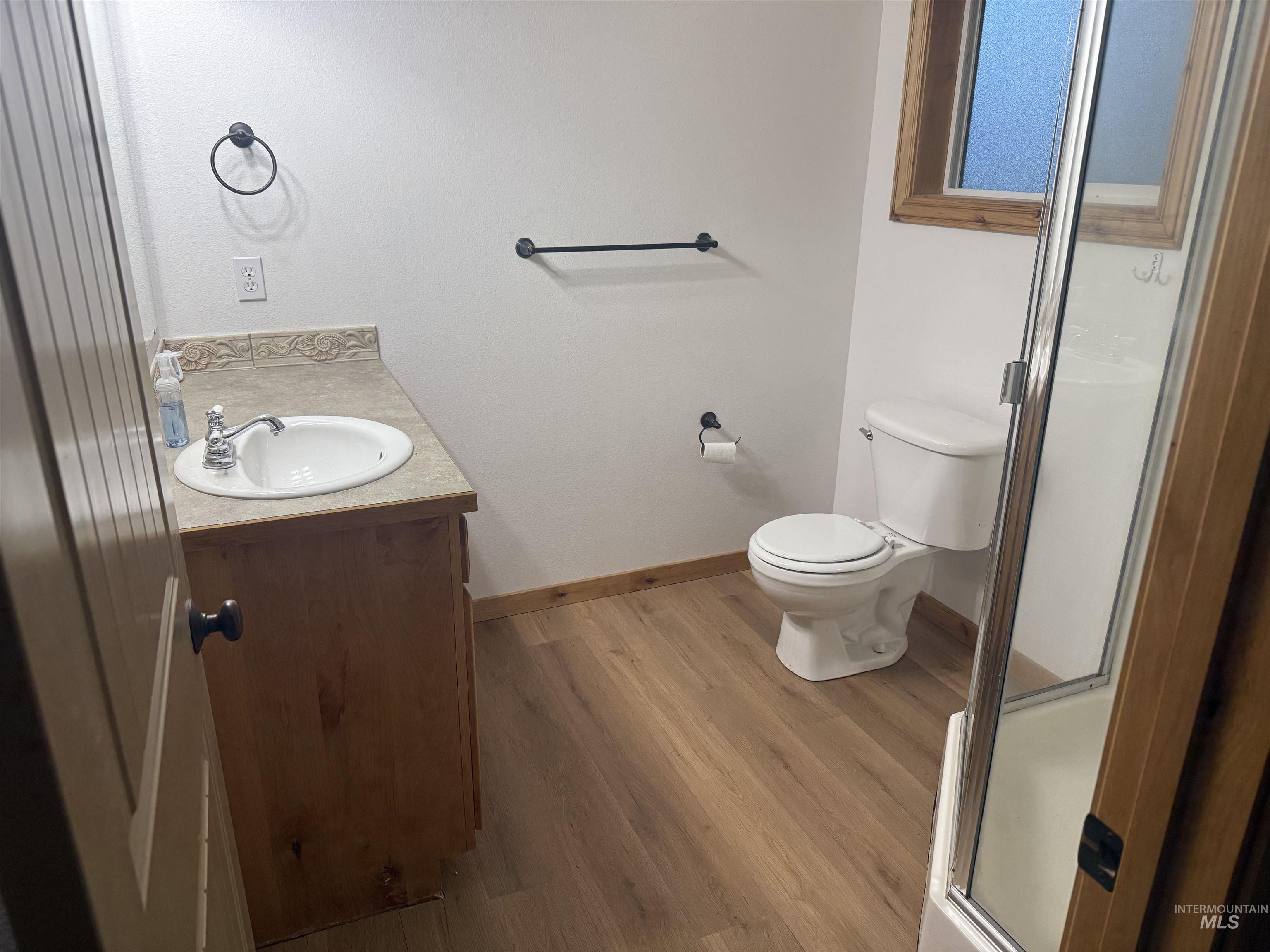 Full bathroom with vanity, a stall shower, and light wood-type flooring