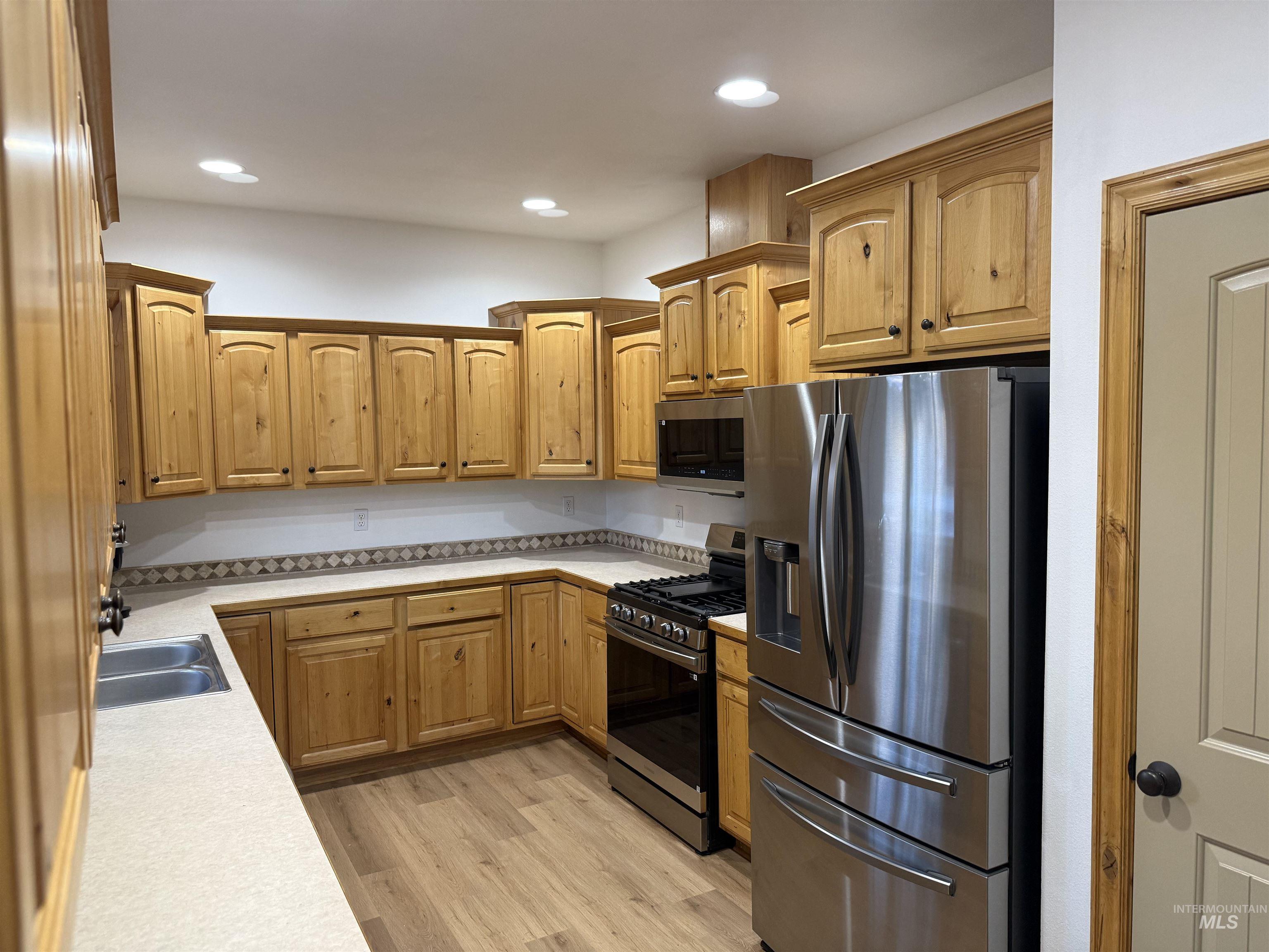 Kitchen featuring stainless steel appliances, light countertops, light wood-style floors, and recessed lighting