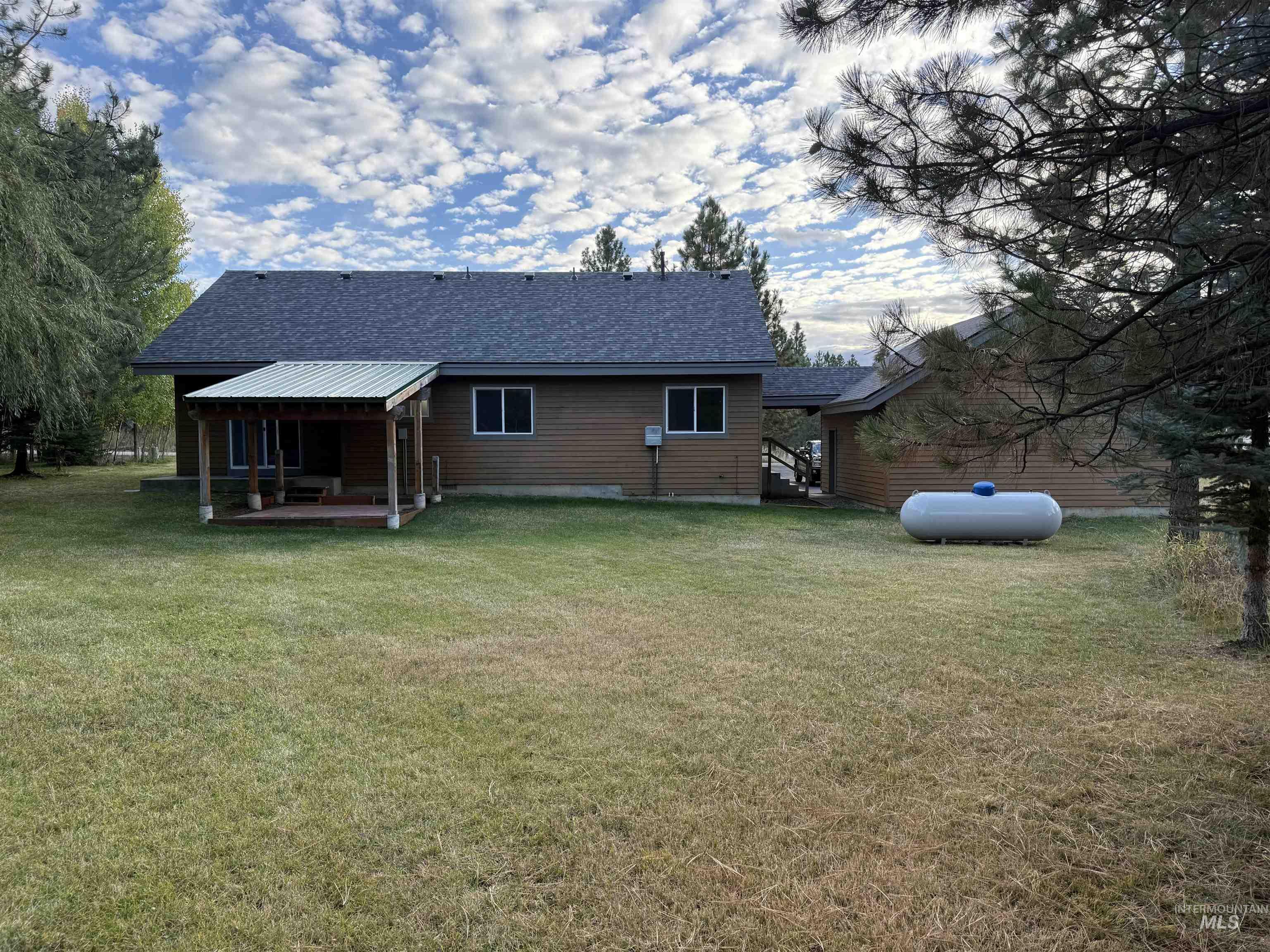 Rear view of house with roof with shingles, a yard, and a patio area